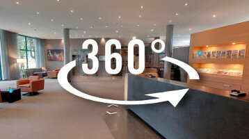 Virtuelle Rundgang ATLANTIC Hotel Airport in Bremen 360-Grad-Ansicht der modernen Lobby im ATLANTIC Hotel Airport Bremen mit Sitzbereichen und Rezeption.