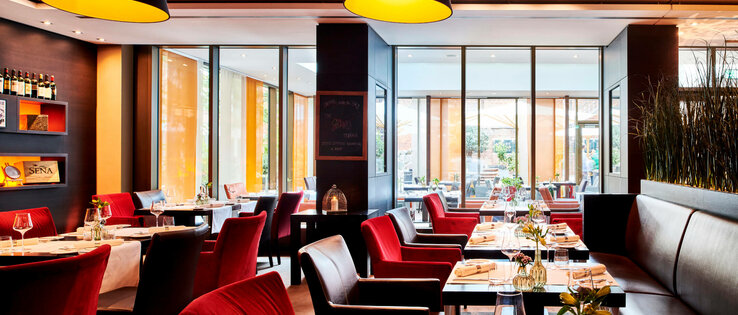 Restaurant alto im ATLANTIC Grand Hotel Bremen Modernes Restaurant im ATLANTIC Grand Hotel Bremen mit eleganten roten Stühlen, gedeckten Tischen und großen Fenstern.