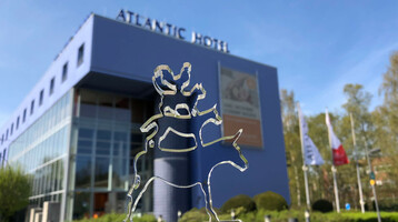 ATLANTIC Hotel Universum in Bremen - Außenaufnahmen ATLANTIC Hotel Universum mit Glasfigur der Bremer Stadtmusikanten im Vordergrund, moderne Architektur, blauer Himmel.