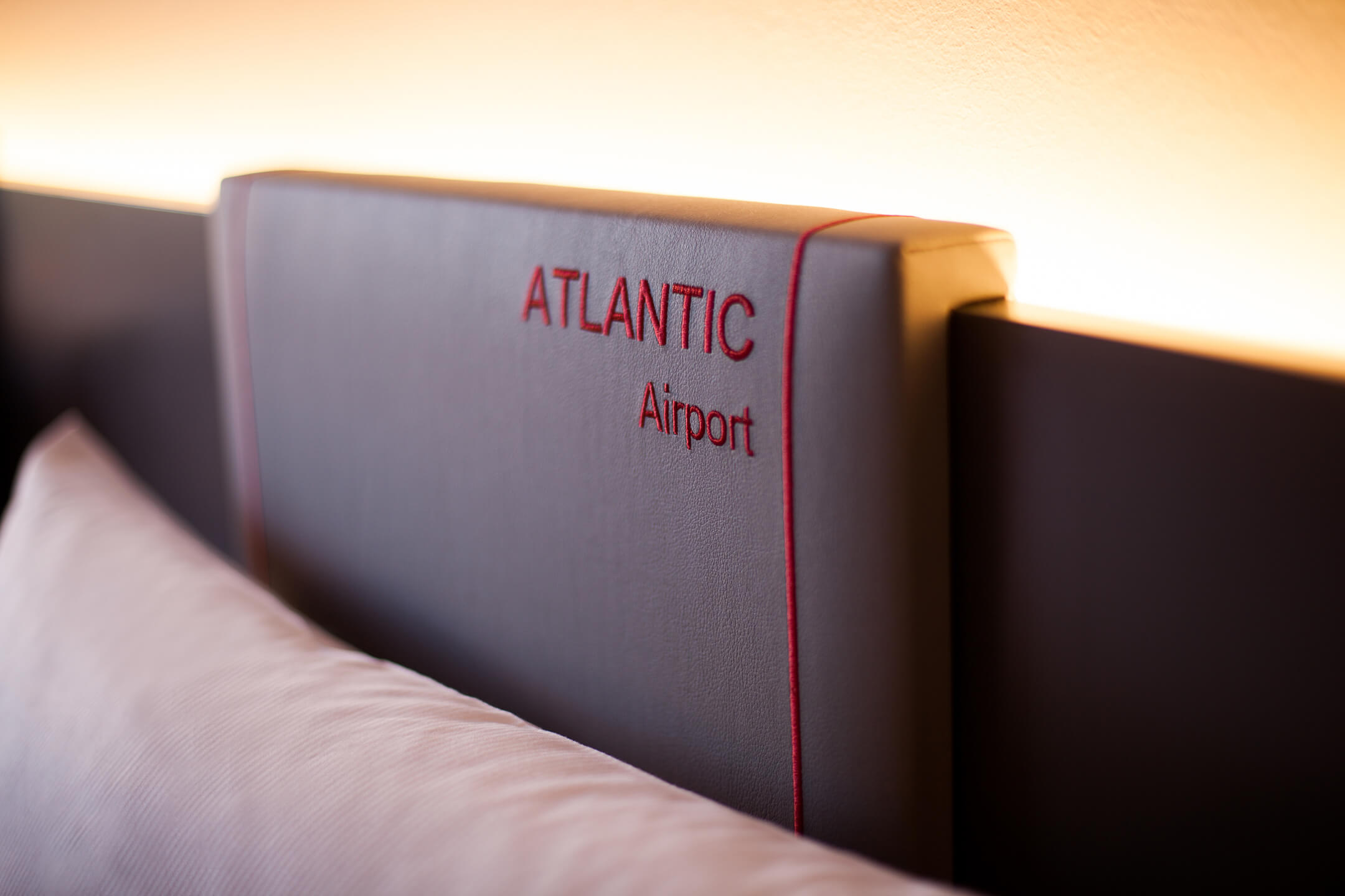 Schriftzug des ATLANTIC Hotel Aiport am Bett