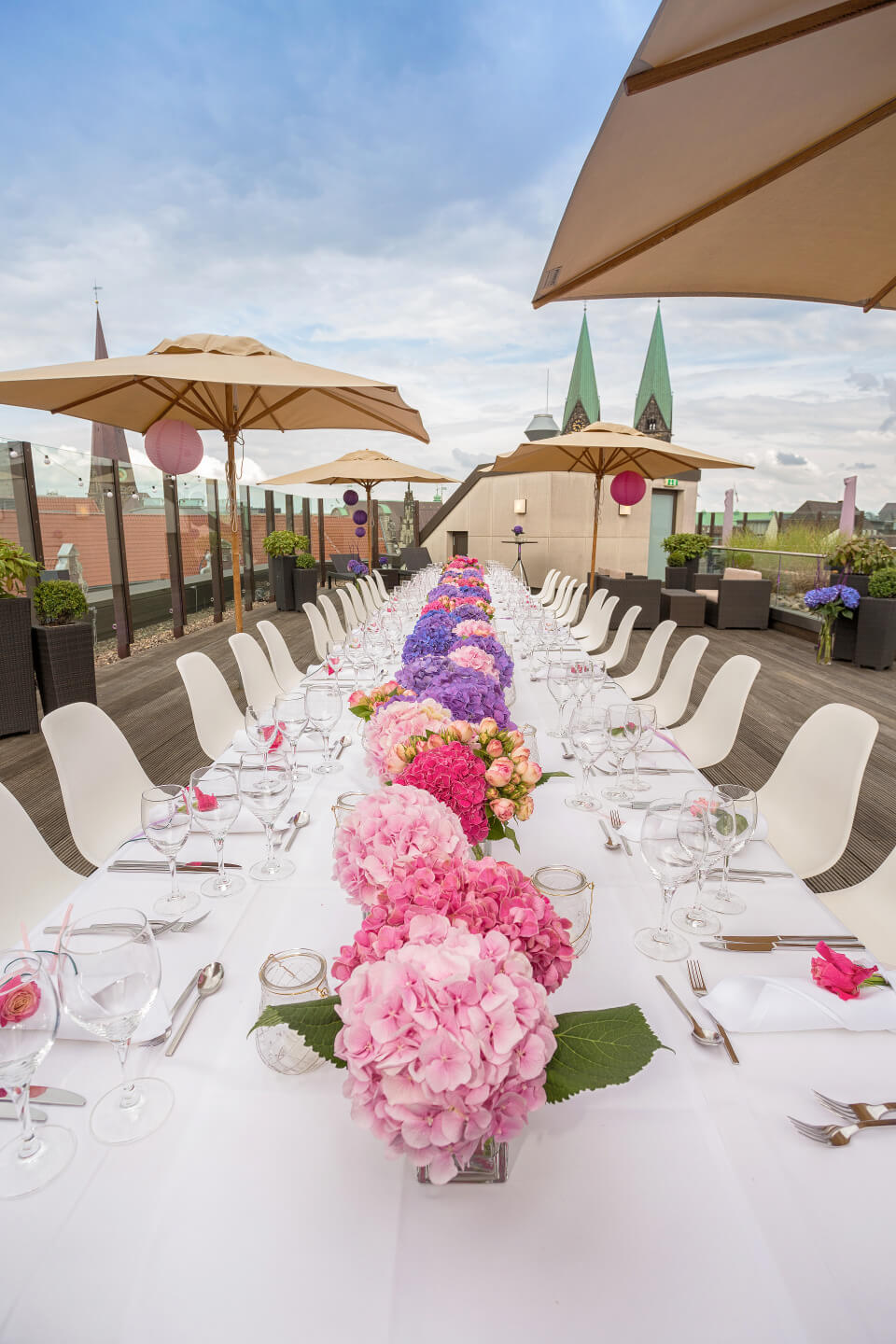 Festively laid table on the terrace of the ATLANTIC Grand Hotel Bremen with flowers and parasols.