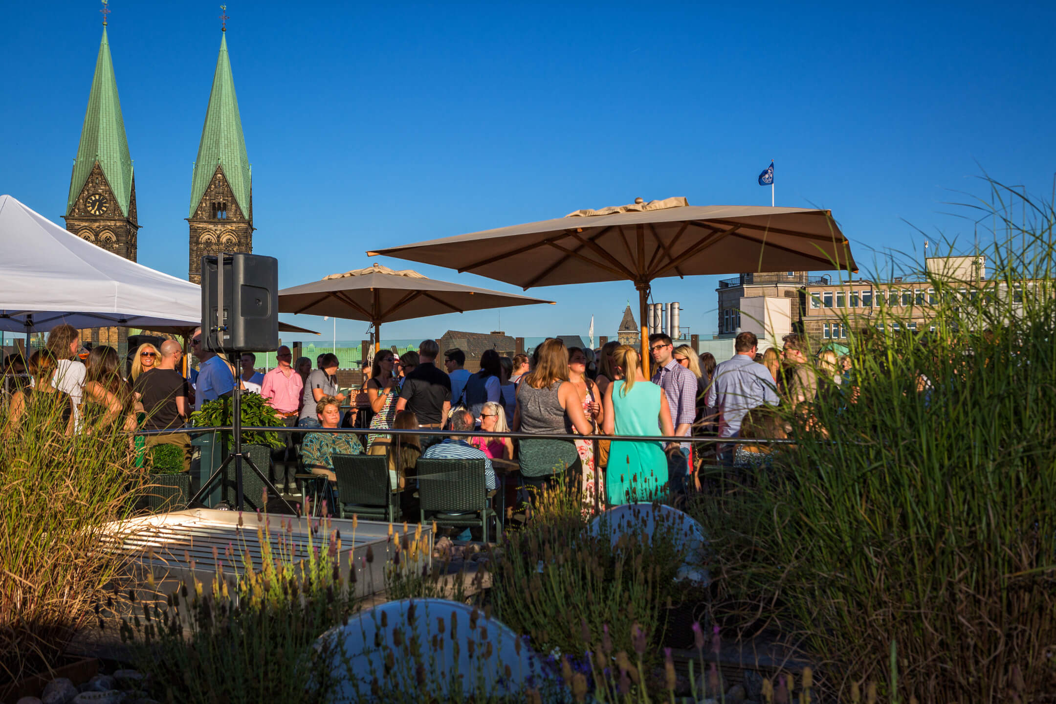 People enjoy an event on the hotel terrace with a view of the towers of Bremen Cathedral.