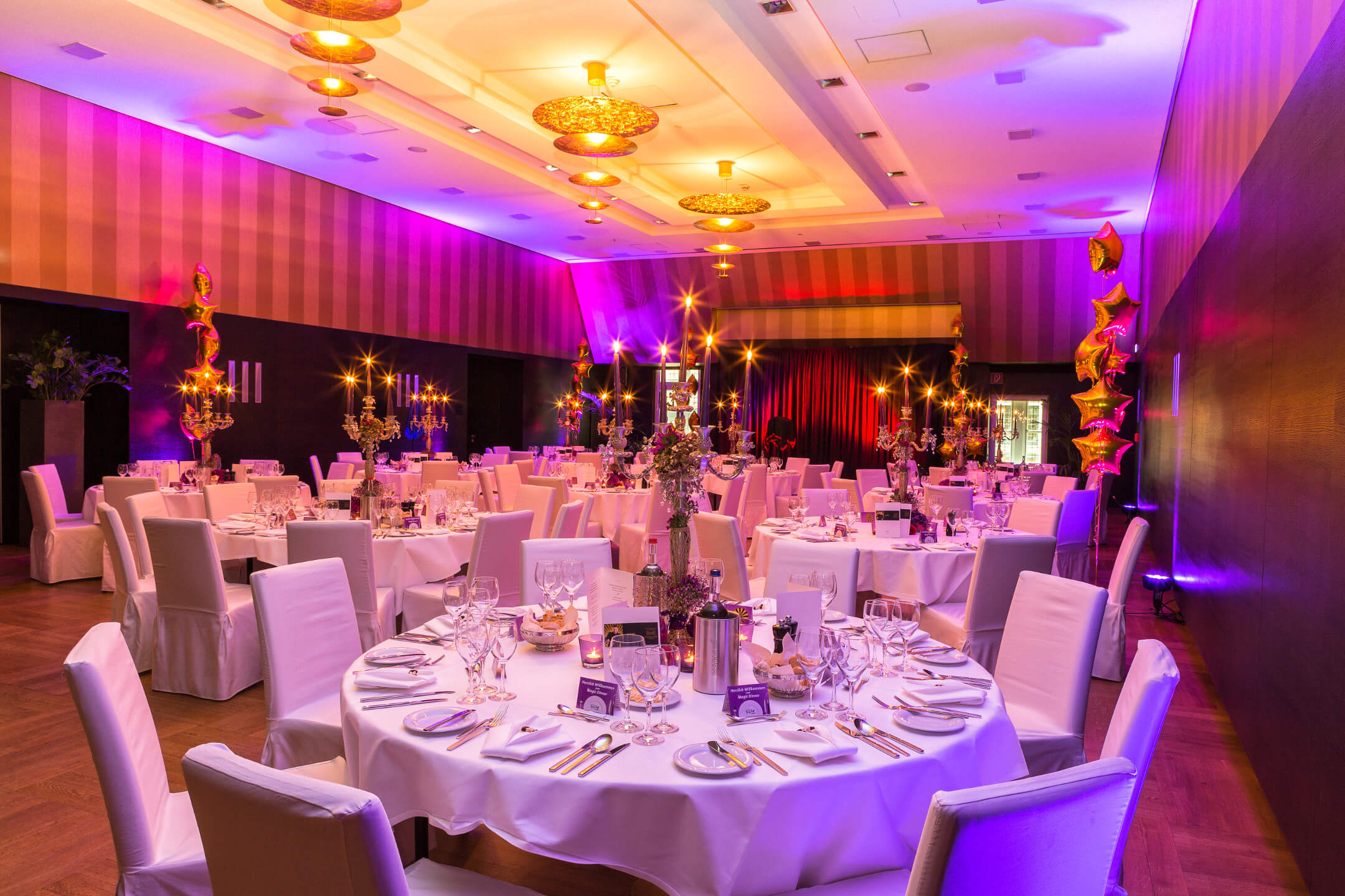 Elegant, festively lit banquet hall with round tables set in white at the ATLANTIC Grand Hotel Bremen.