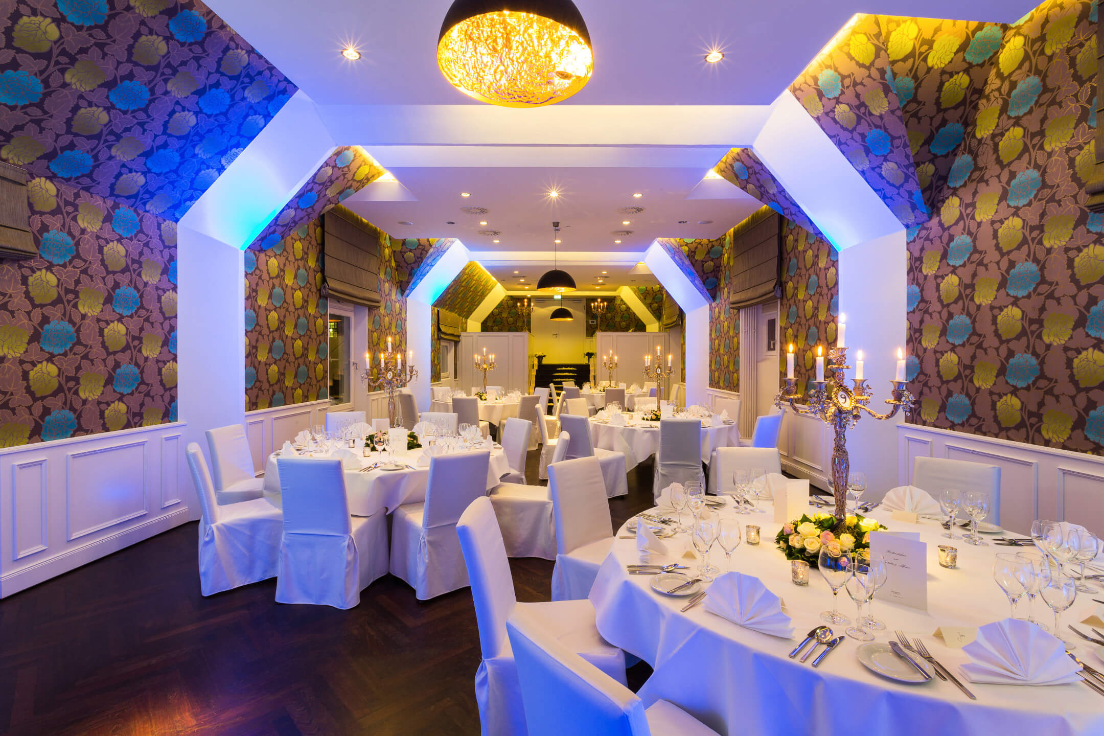 Elegant banquet hall in the ATLANTIC Grand Hotel Bremen with round, white-clothed tables and stylish chandeliers.