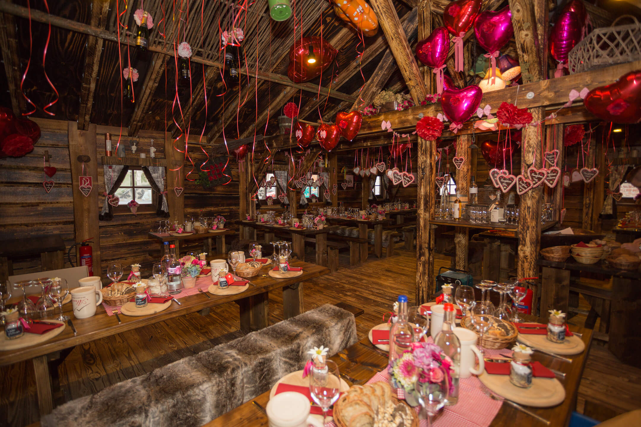 Cozy wooden hut, festively decorated with heart balloons and laid tables for a celebration at the ATLANTIC Grand Hotel Bremen.