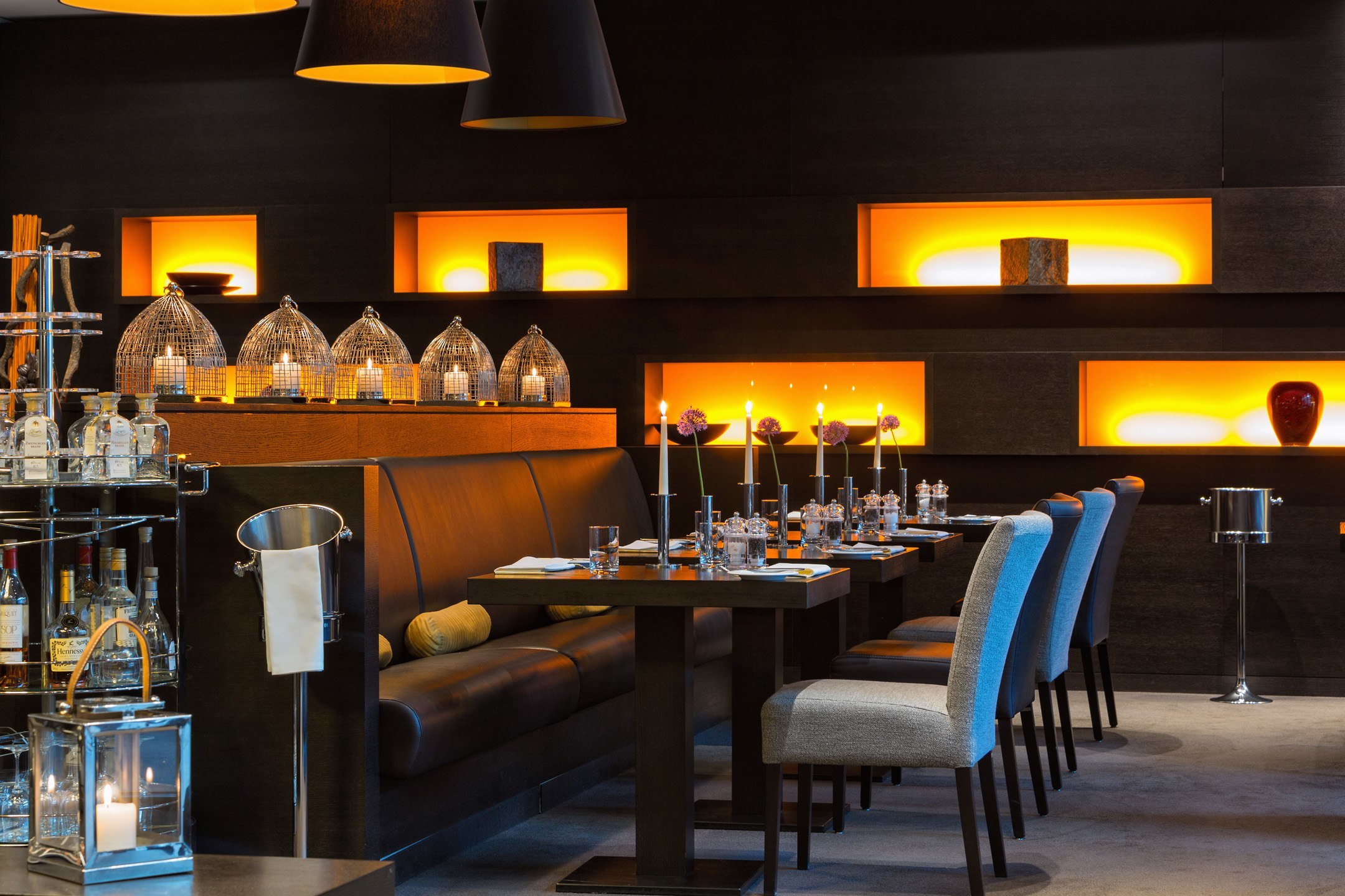 Elegant restaurant with candlelight, modern seating and warmly lit wall shelves at the ATLANTIC Grand Hotel Bremen.
