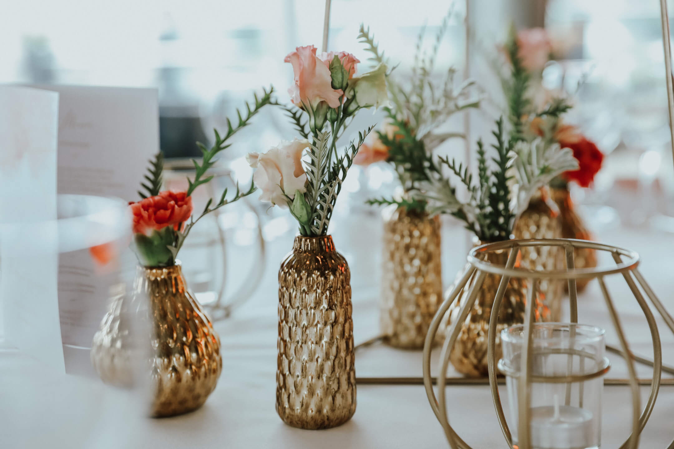 Bunte Hochzeitsblumen in goldenen Vasen 