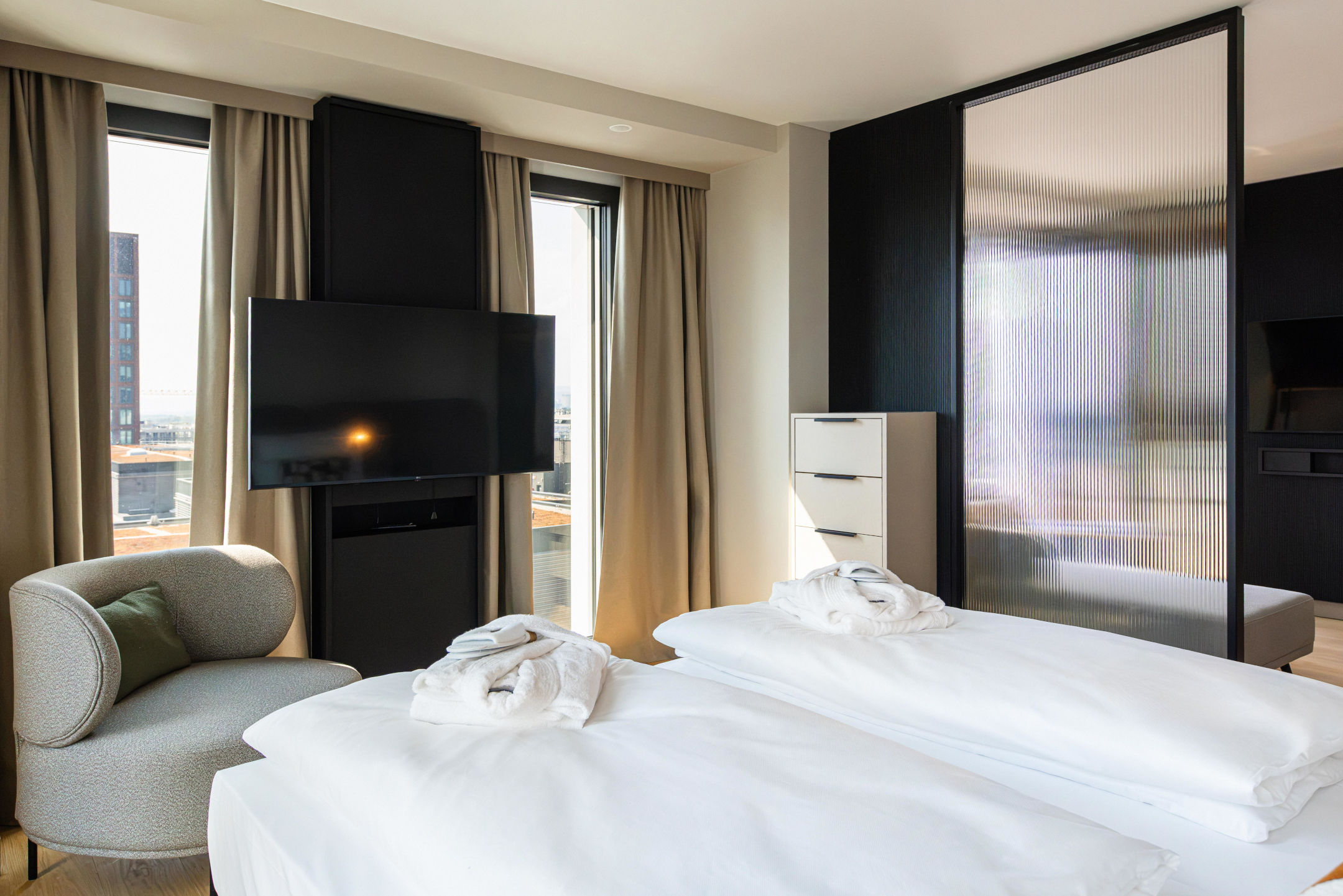 Ausblick vom Bett mit Fernseher, Kommode und Sessel.