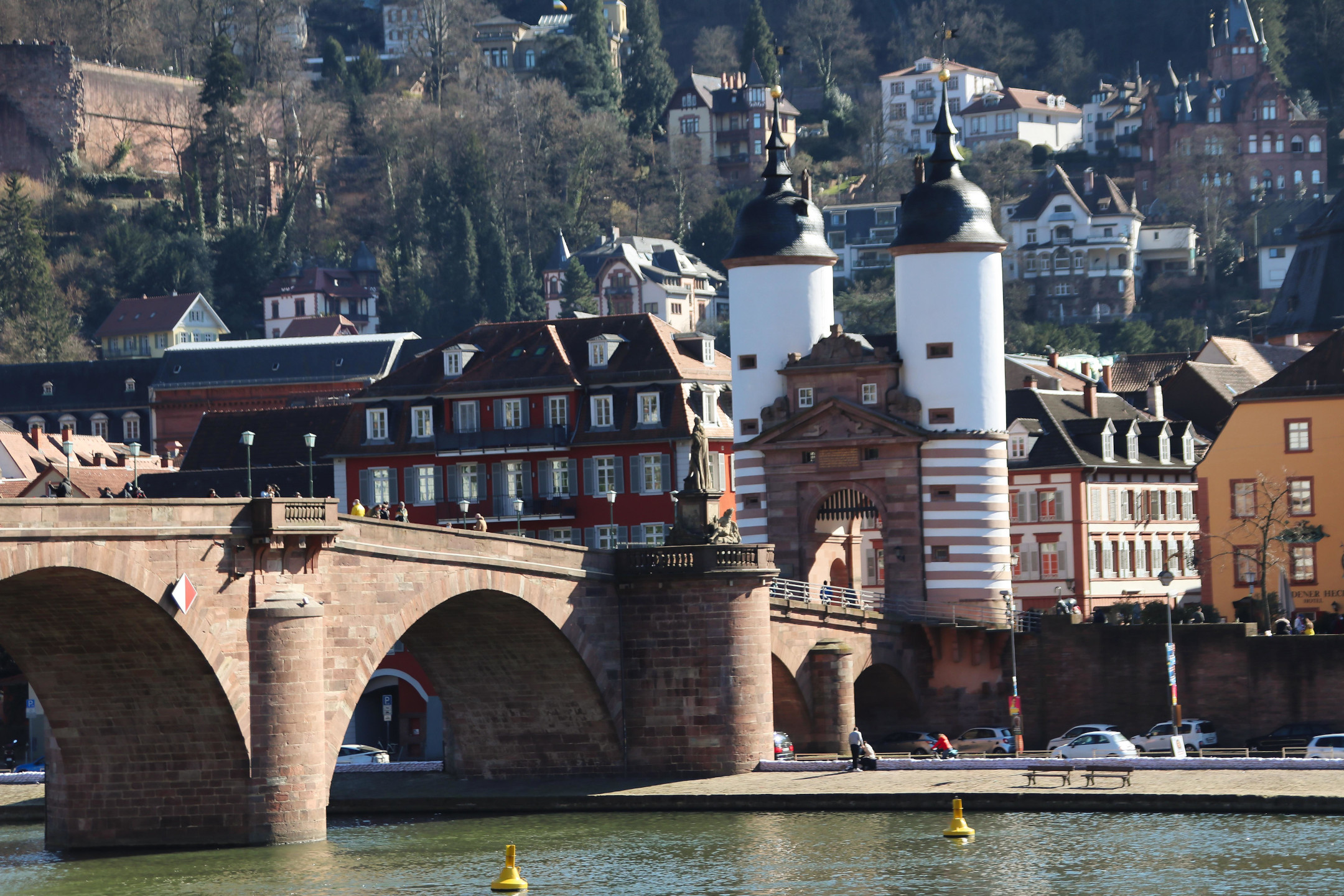 Historic bridge with gates and old town buildings in the background, surrounded by wooded hills.