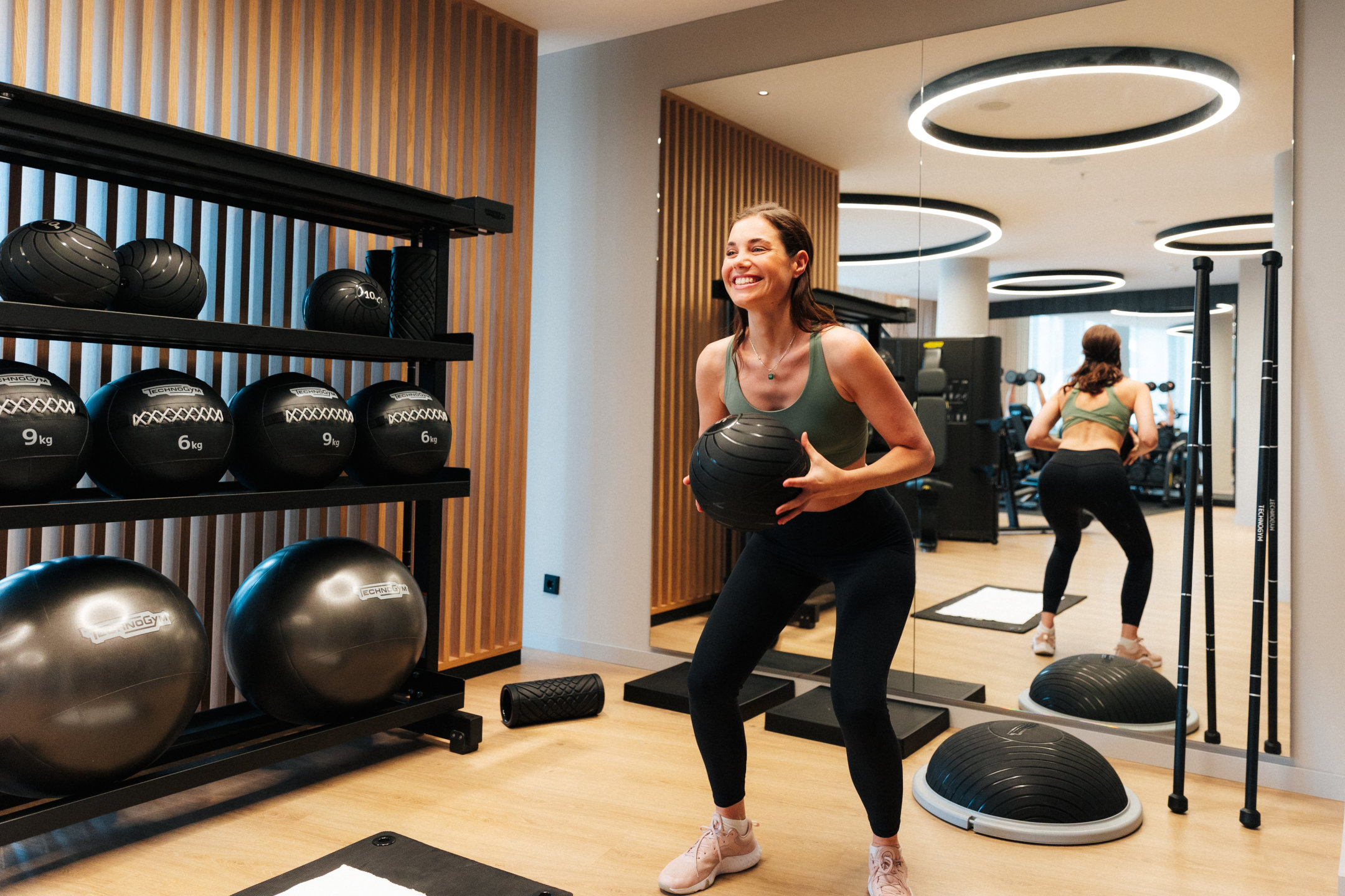 Fitnessraum im Hotel - eine Frau macht Sport mit einem Medizinball in den Händen