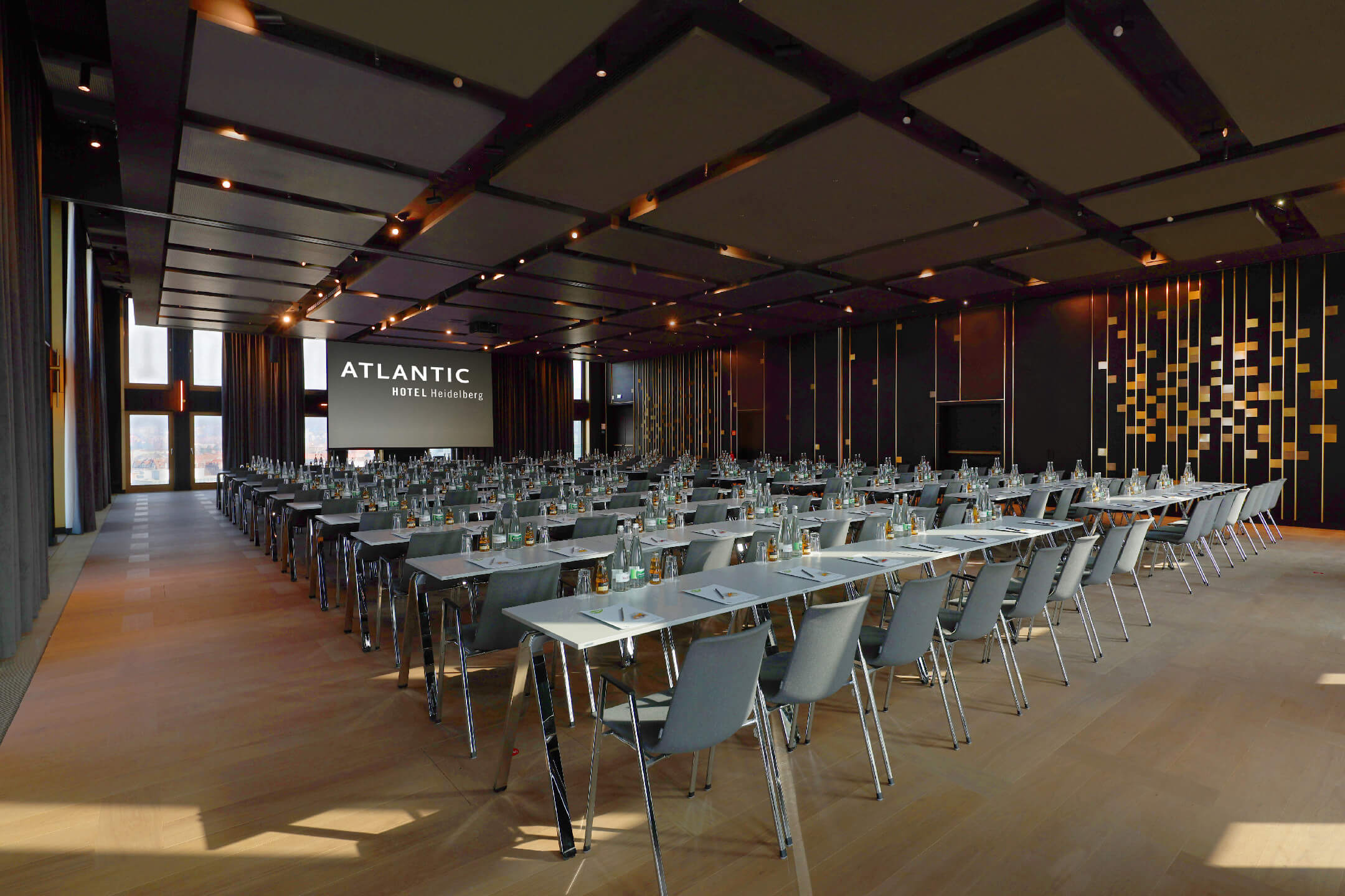 Parlamentarisch bestuhlter Ballsaal im ATLANTIC Hotel Heidelberg mit Blick auf die ausgefahrene Leinwand
