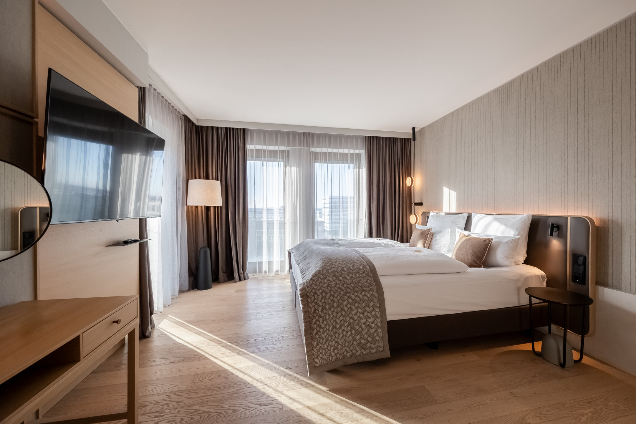 Blick auf das Bett und die sonnendurchfluteten Fenster