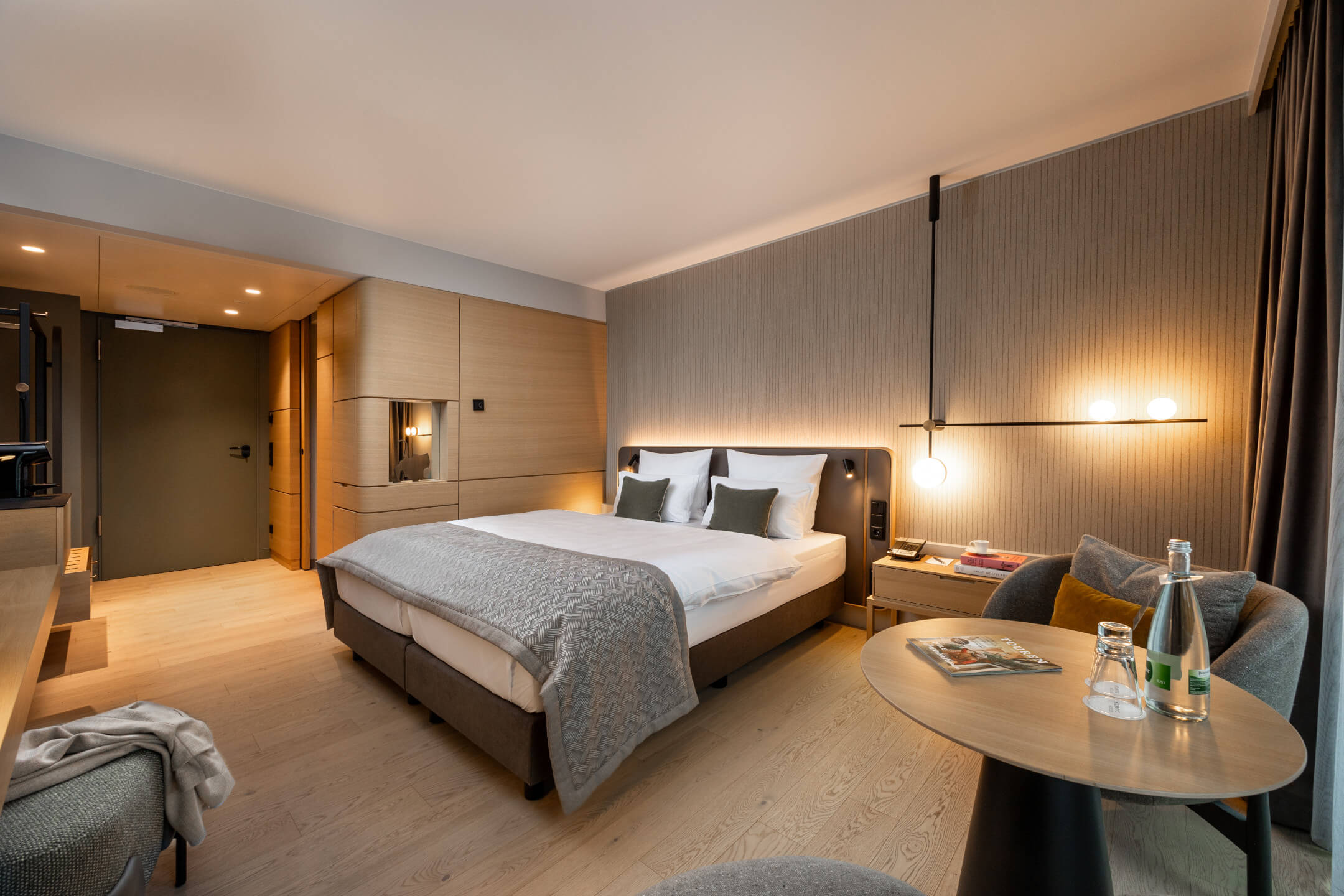 Modernes Hotelzimmer mit Doppelbett, eleganter Beleuchtung, Sitzbereich und Holzakzenten im ATLANTIC Hotel Heidelberg.