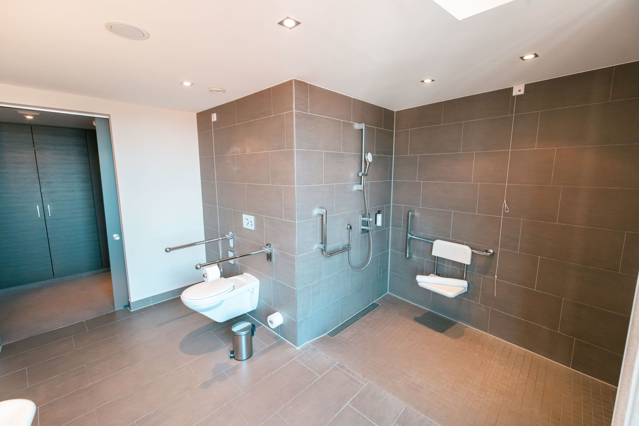 WC mit Haltegriffen und große Dusche mit Sitz im Bad