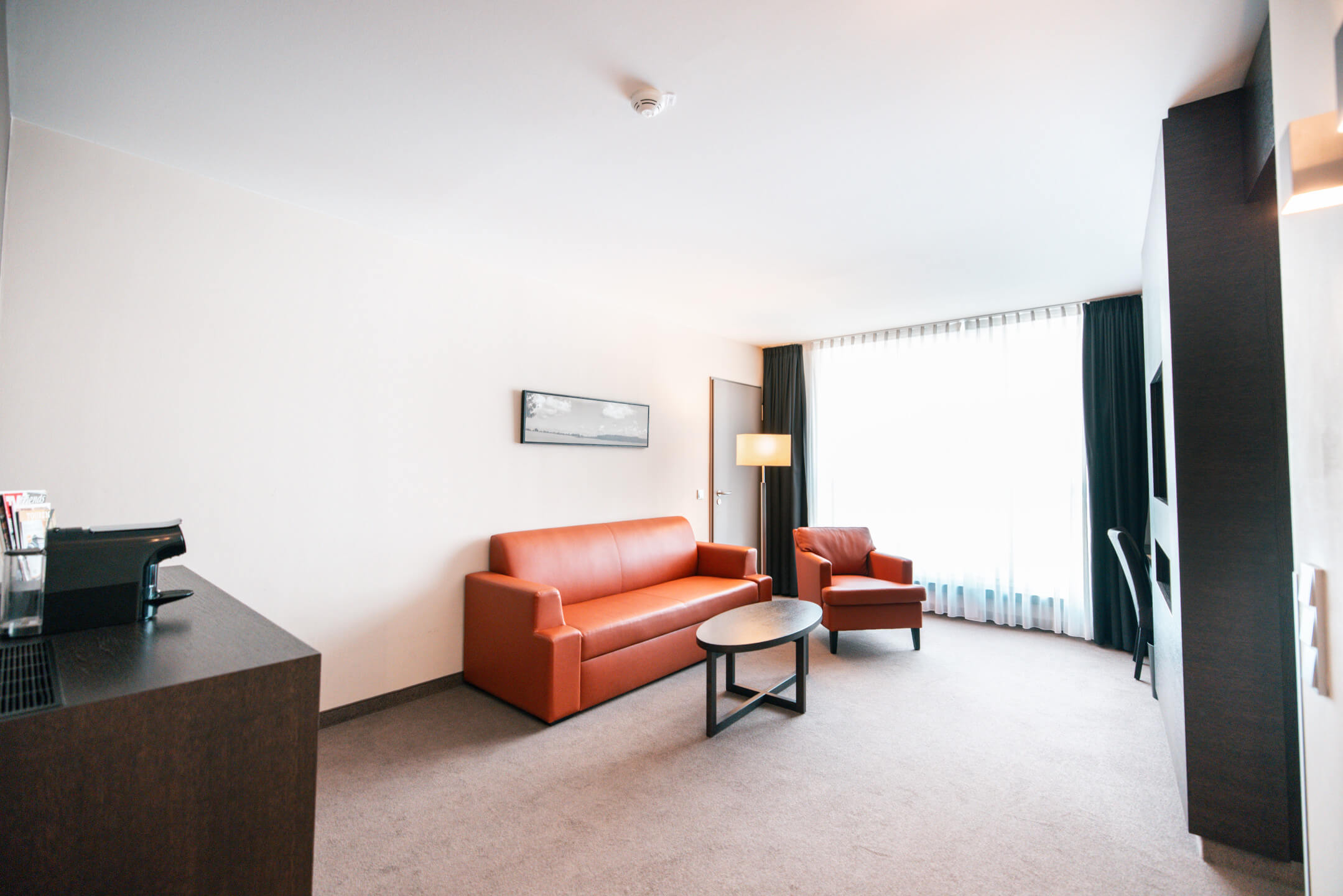 Wohnraum der Suite im ATLANTIC Hotel Lübeck mit Couch und Sessel