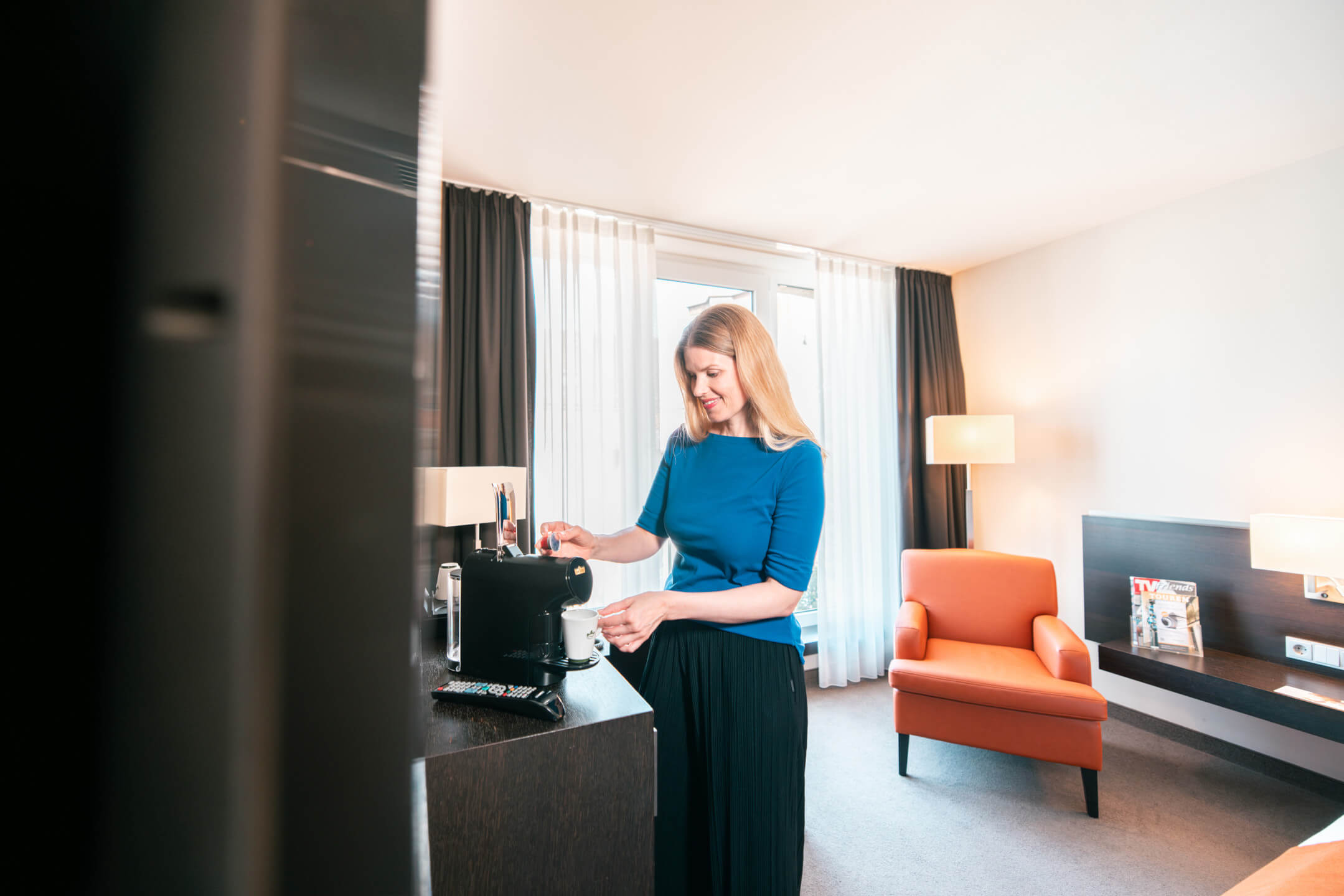 Frau macht sich einen Kaffee im Hotelzimmer des ATLANTIC Hotel Lübeck