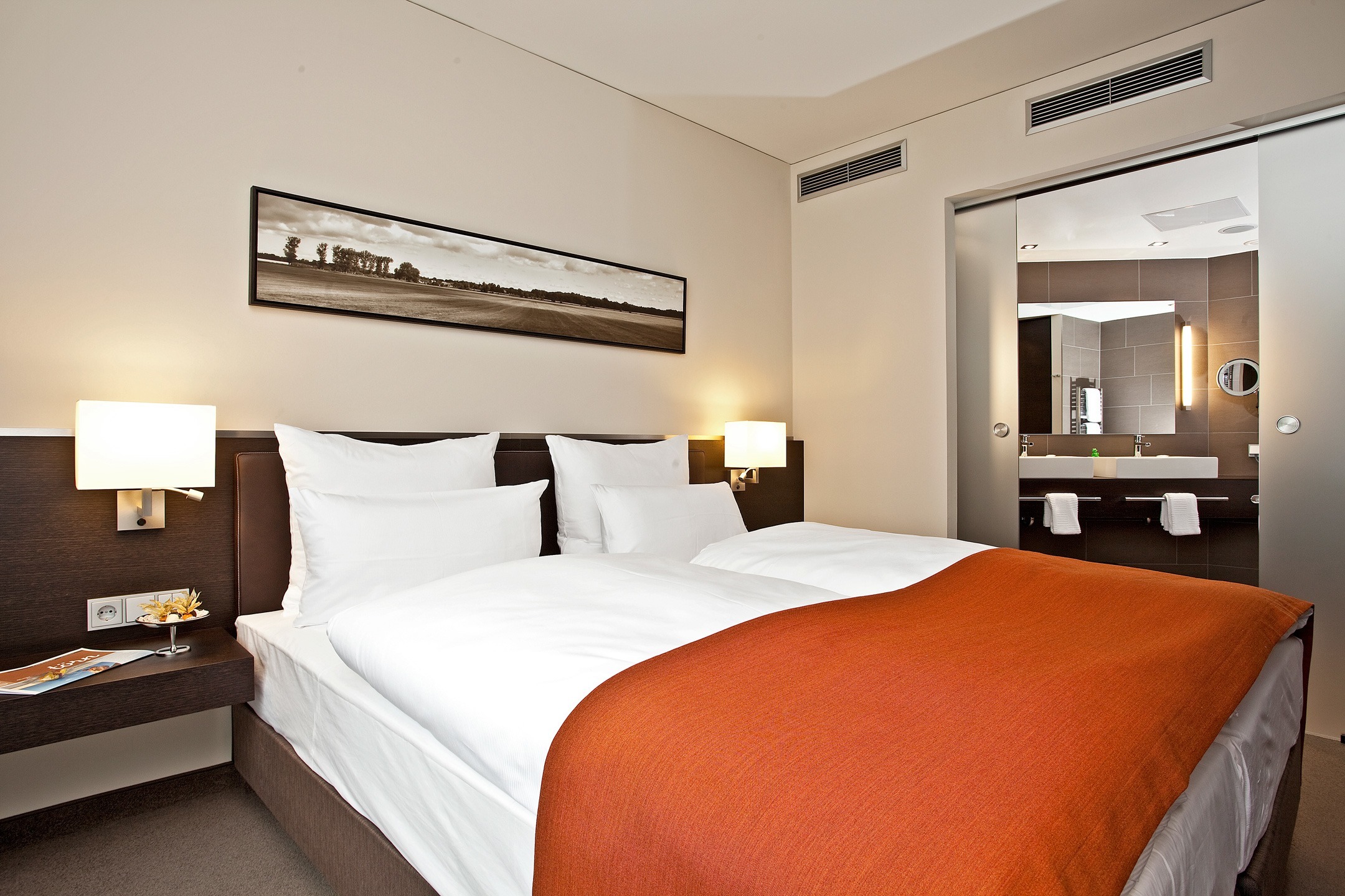 Suite mit Blick ins Bad und auf Doppelbett im ATLANTIC Hotel Lübeck