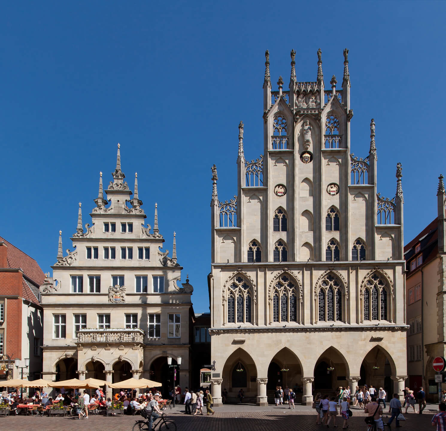 Historical town hall and "Stadtweinhaus" in Münster Historic buildings on Prinzipalmarkt in Münster in sunny weather, with people and cafés in the foreground.