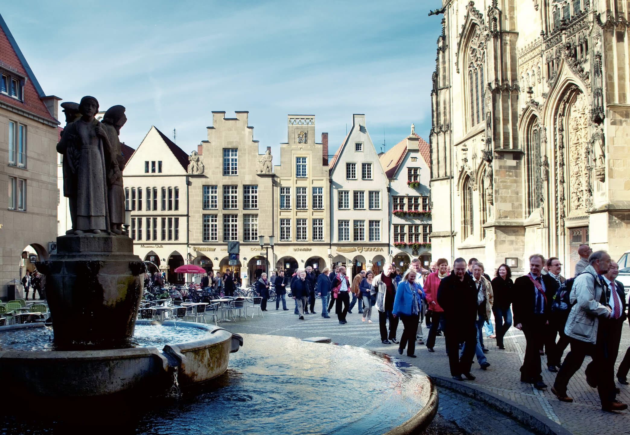 Lambertibrunnen in Münster Historic square in Münster with fountain, Gothic church and passers-by.