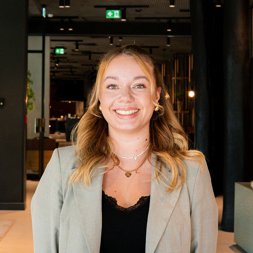 Lächelnde Frau in Business-Kleidung im modernen, stilvollen Lobbybereich des ATLANTIC Hotel Münster.