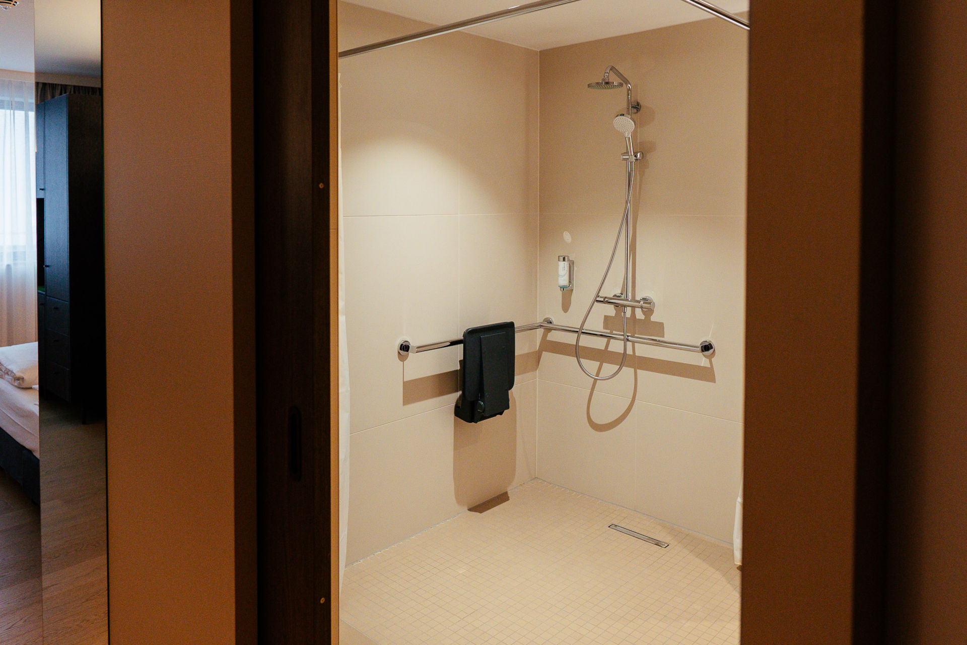 Ansicht der Dusche mit Sitz und Griffhaltern im barrierefreien Zimmer