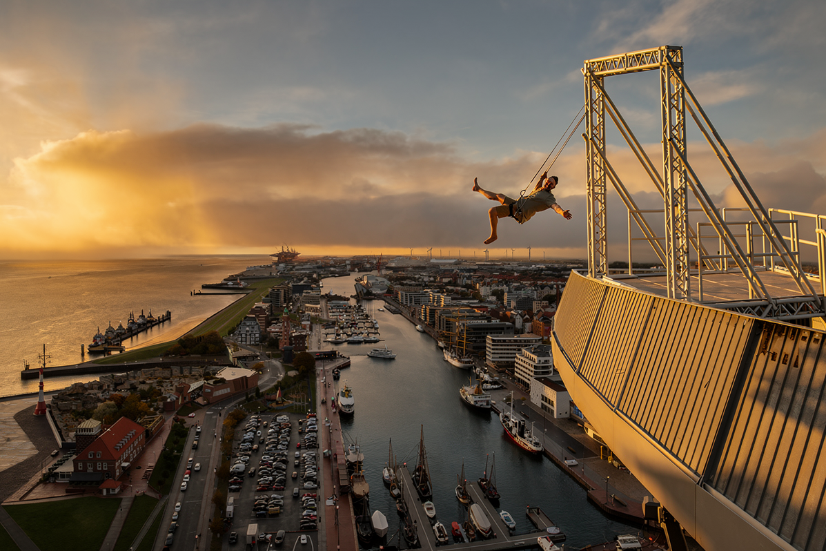 Eine Person die auf der High Swing auf dem ATLANTIC Hotel Sail City schaukelt. KI Mockup