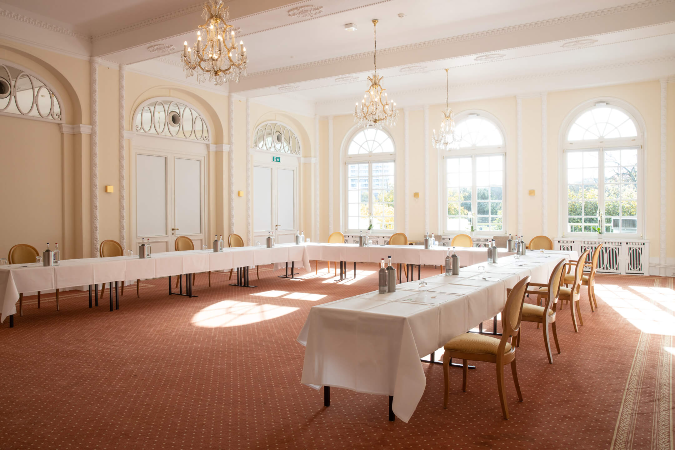 Veranstaltungsraum Bremen 5 | ATLANTIC Grand Hotel Travemünde Heller Konferenzraum im ATLANTIC Grand Hotel Travemünde mit eleganten Kronleuchtern und gedeckten Tischen.