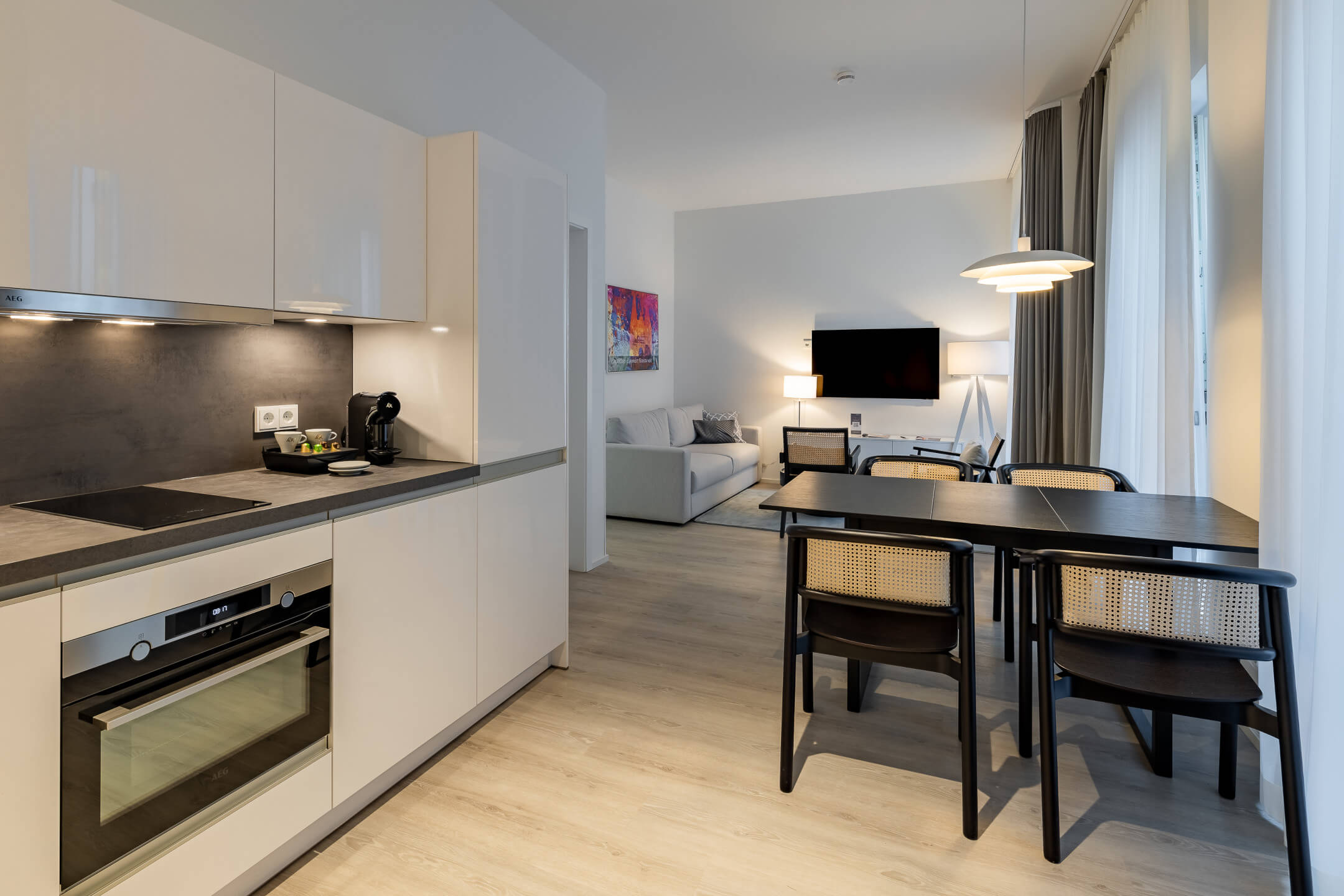 Modern suite with kitchen, dining table, sofa and TV at the ATLANTIC Grand Hotel Travemünde.