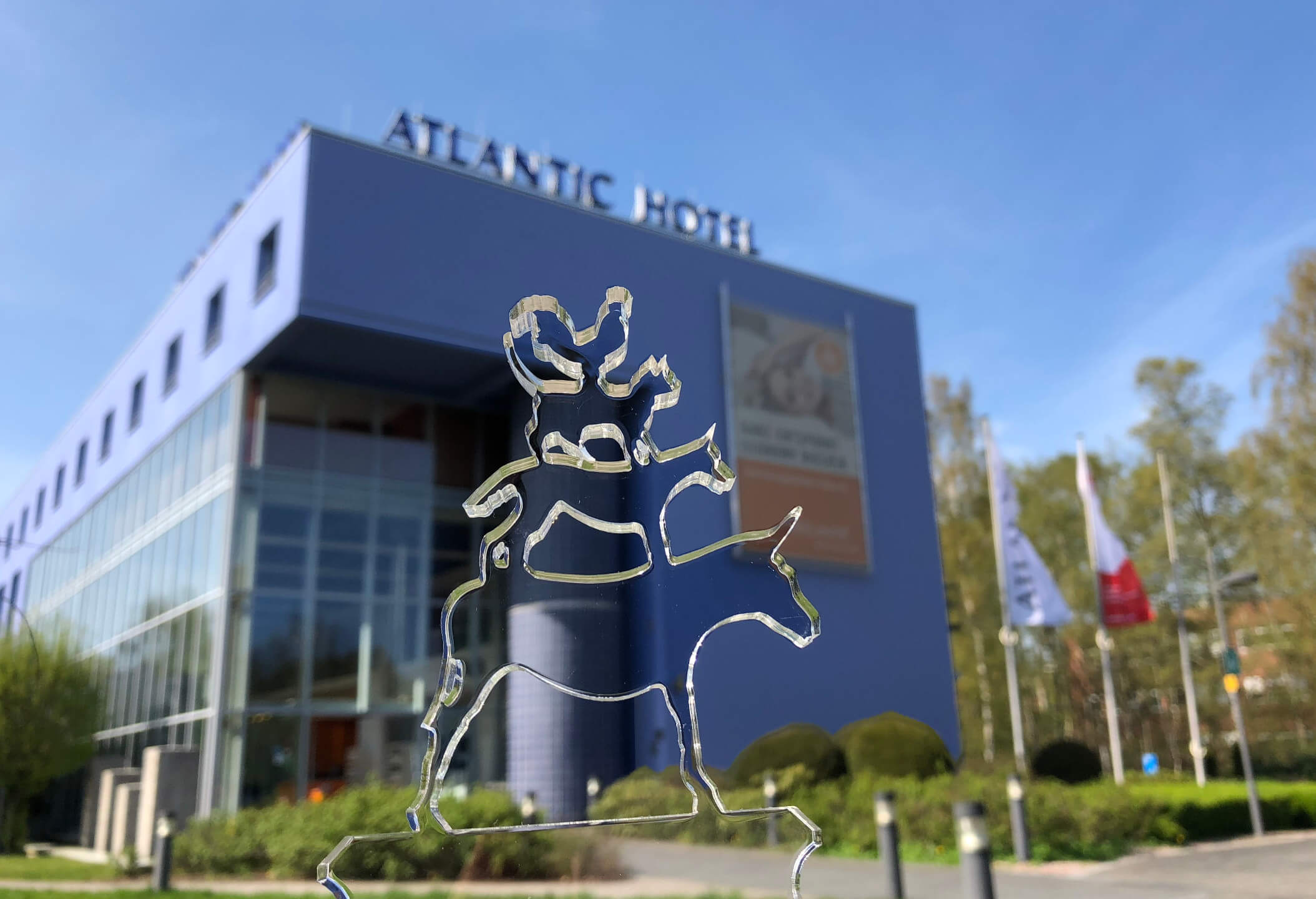 ATLANTIC Hotel Universum mit Glasfigur der Bremer Stadtmusikanten im Vordergrund, moderne Architektur, blauer Himmel.