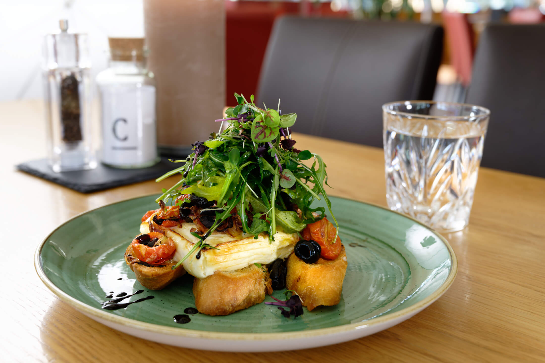Ein Teller mit Halloumi, Rucola und Tomaten auf Brot, serviert im ATLANTIC Hotel Universum Bremen.