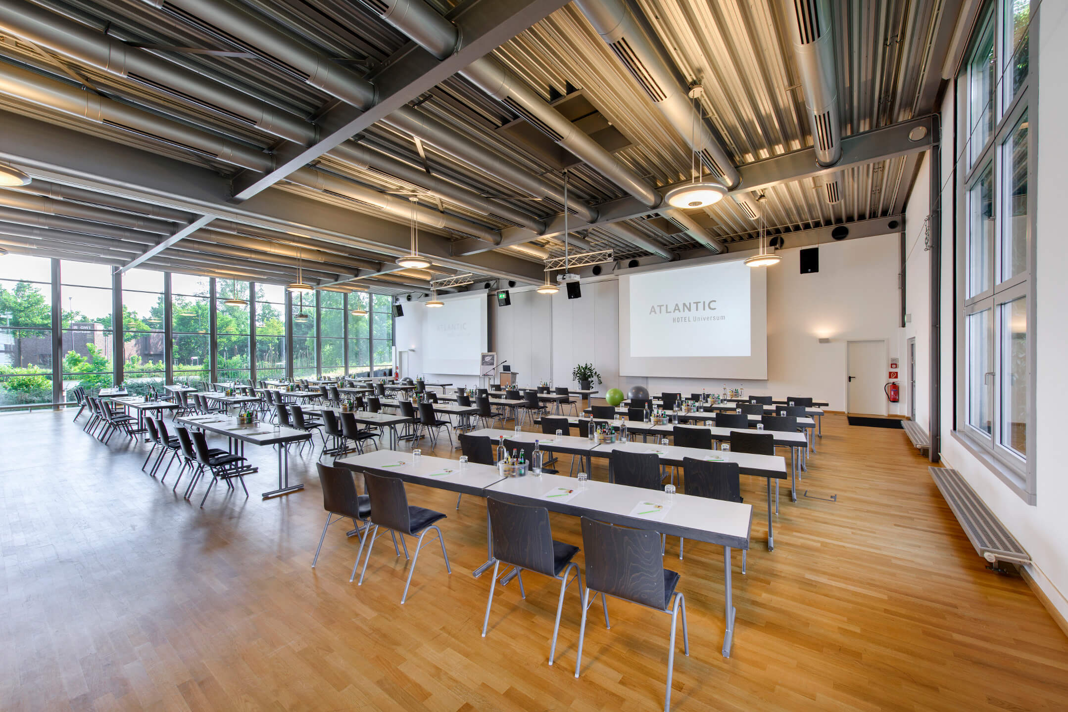 Moderner Konferenzraum im ATLANTIC Hotel Universum mit großen Fenstern und Tagungstischen.