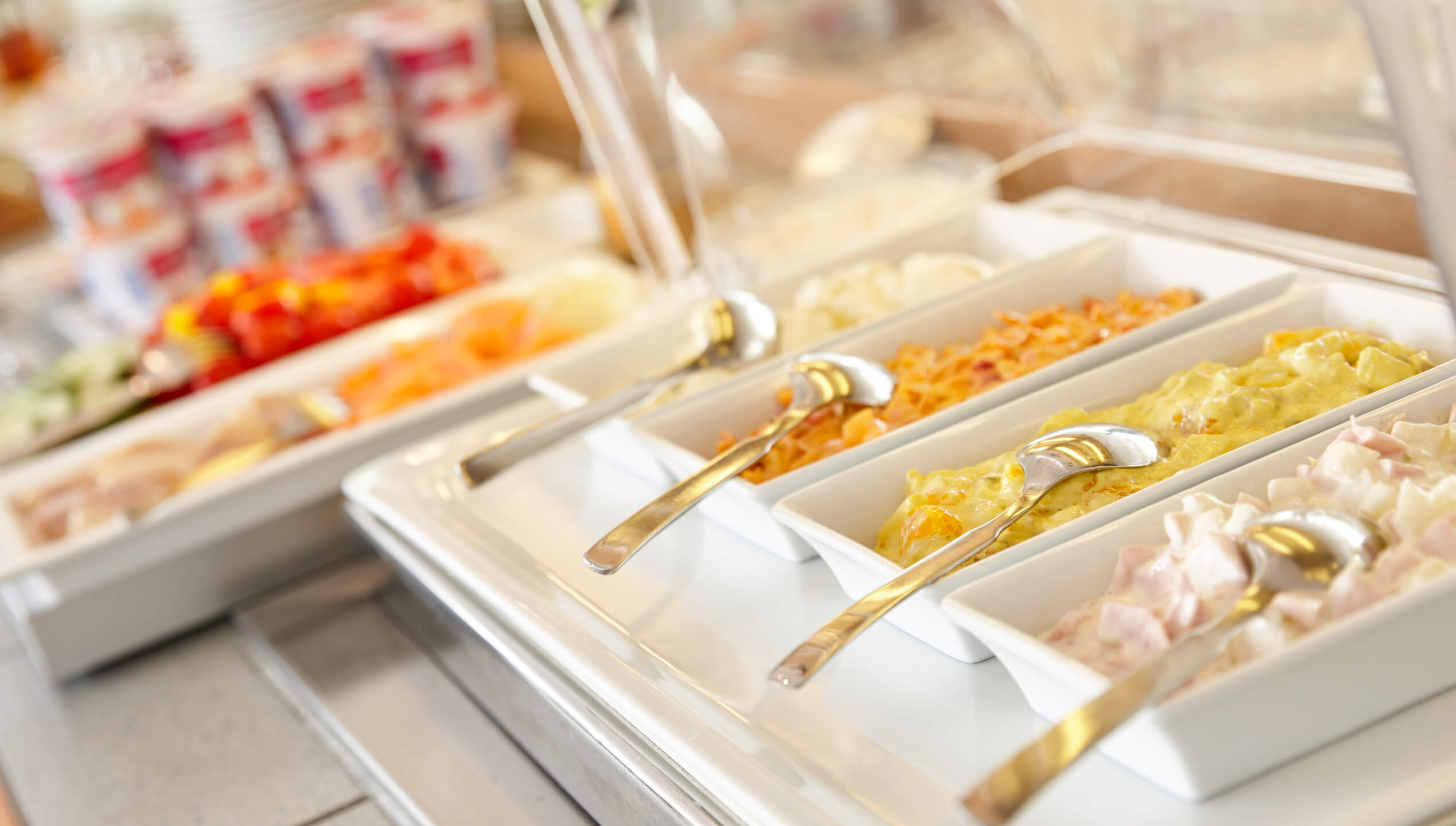 Frühstücksbuffet mit verschiedenen Salaten und Joghurtbechern im ATLANTIC Hotel Vegesack, Bremen.