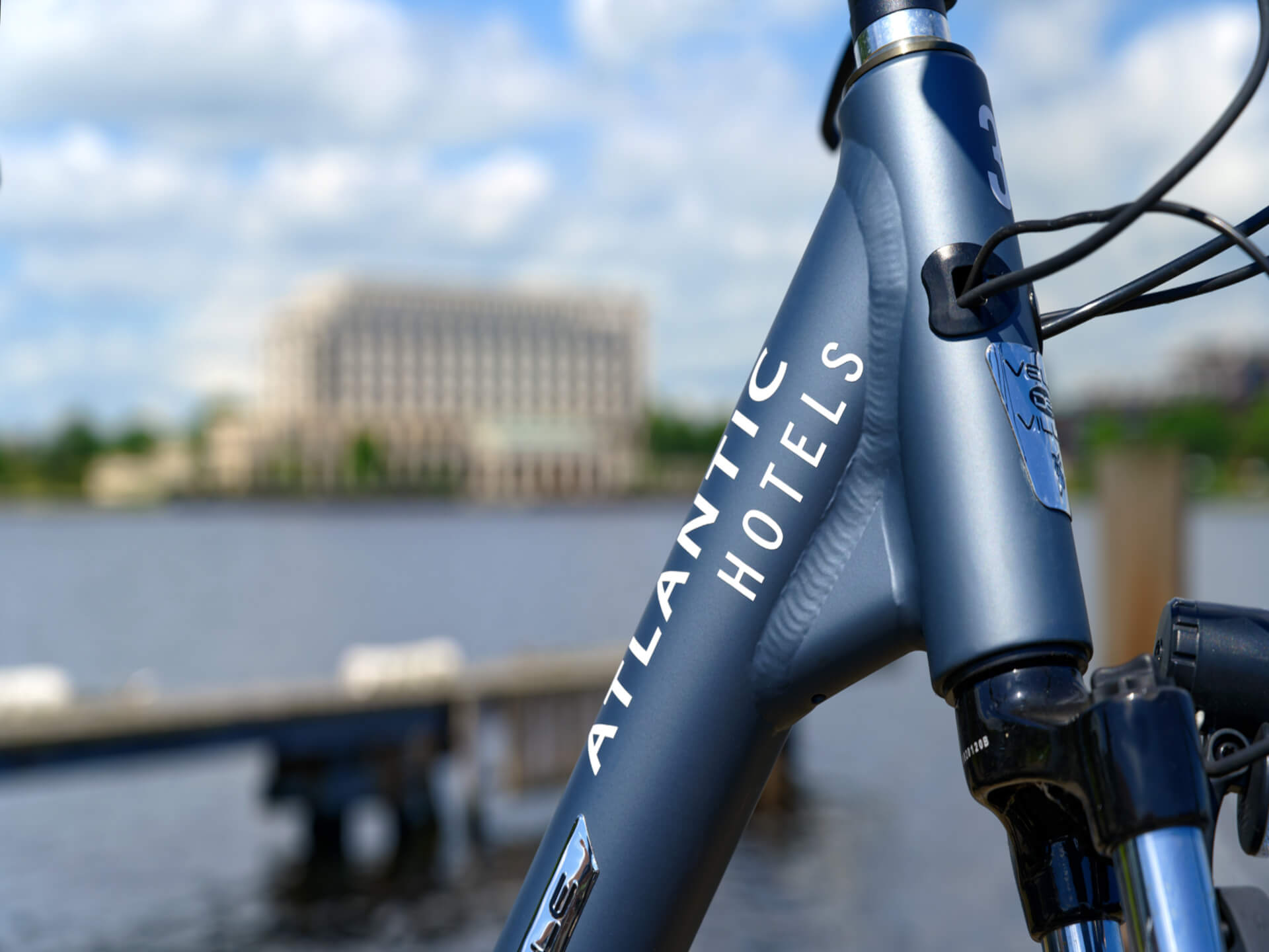 Fahrrad mit "Atlantic Hotels"-Aufschrift vor unscharfem Wasser- und Gebäudehintergrund.
