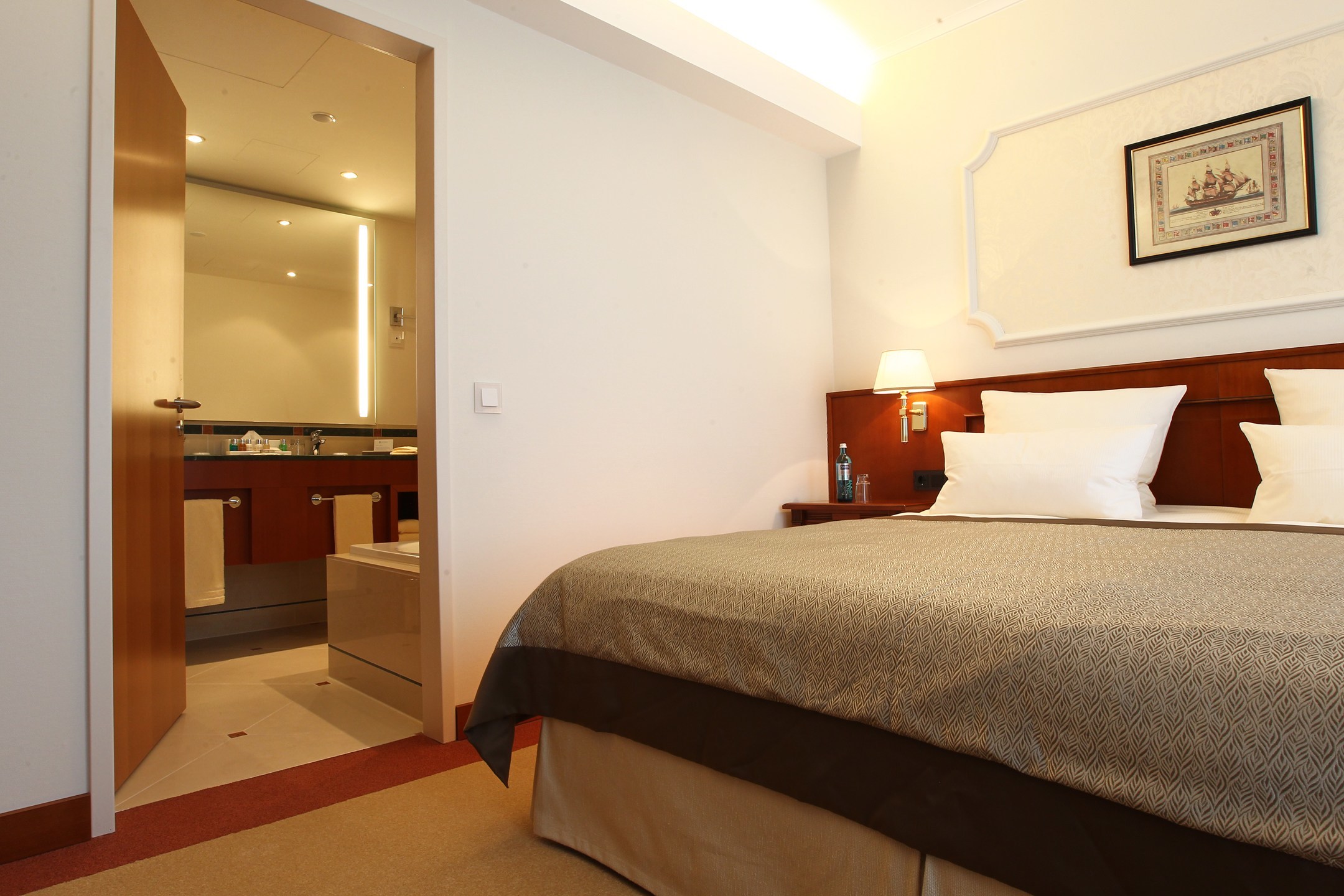 Bedroom of the Gorch Fock Suite with an open door to the bathroom in the ATLANTIC Hotel Wilhelmshaven 