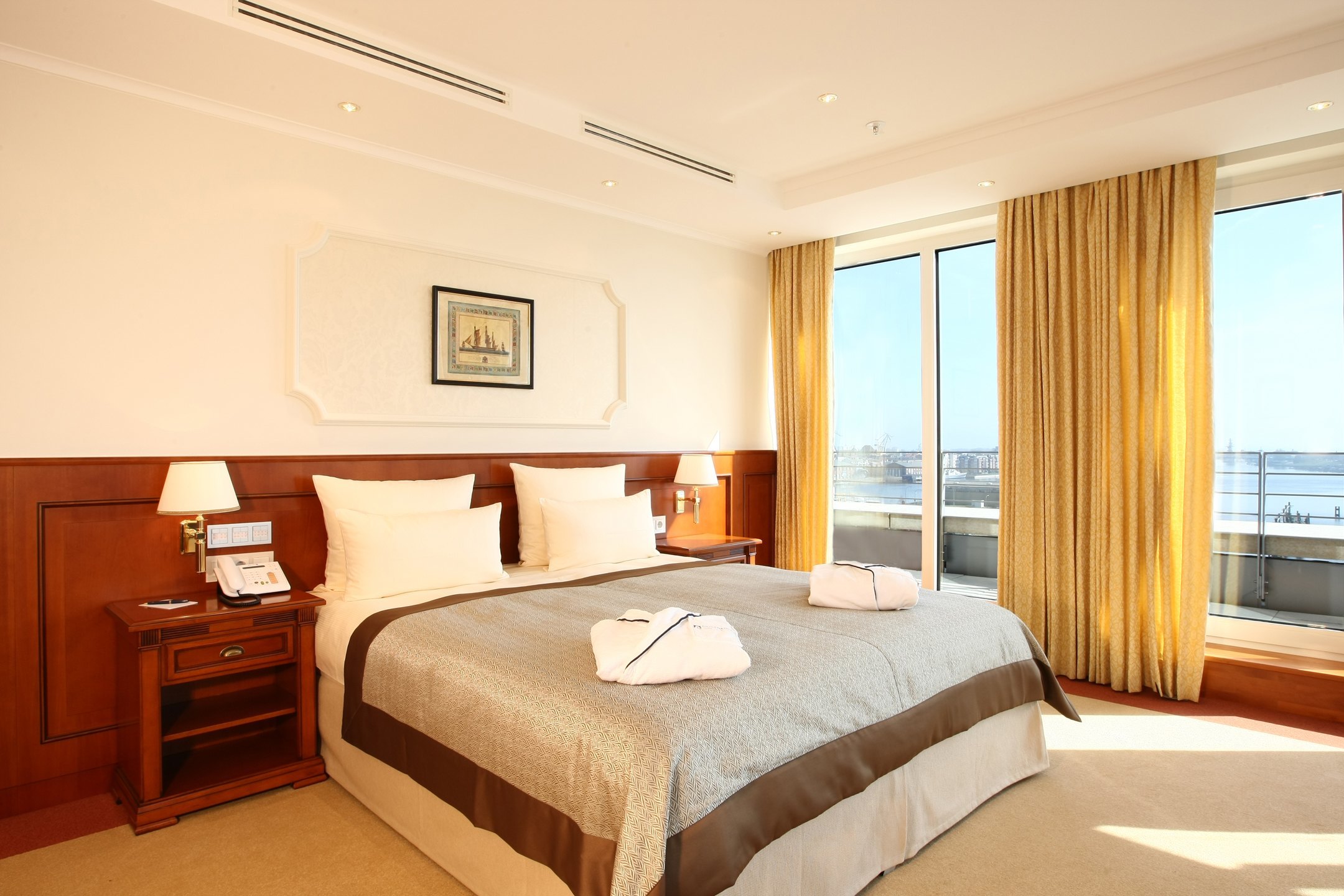 Bedroom of the Kaiser Wilhelm Suite with a big bed and a view over the harbour in the ATLANTIC Hotel Wilhelmshaven