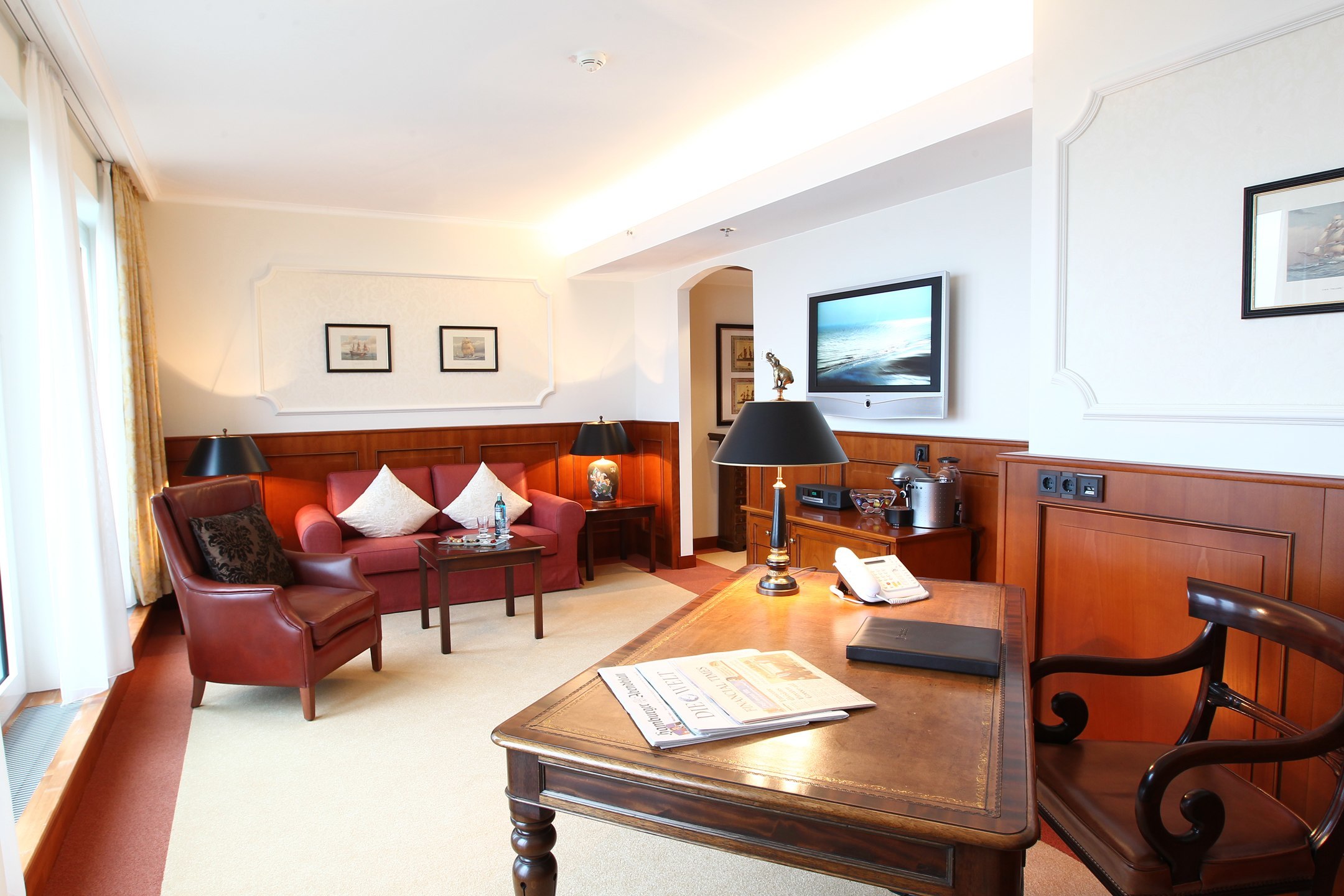 Wohnzimmer mit Sofa und Schreibtisch in der Cutty Sark Suite im ATLANTIC Hotel Wilhelmshaven