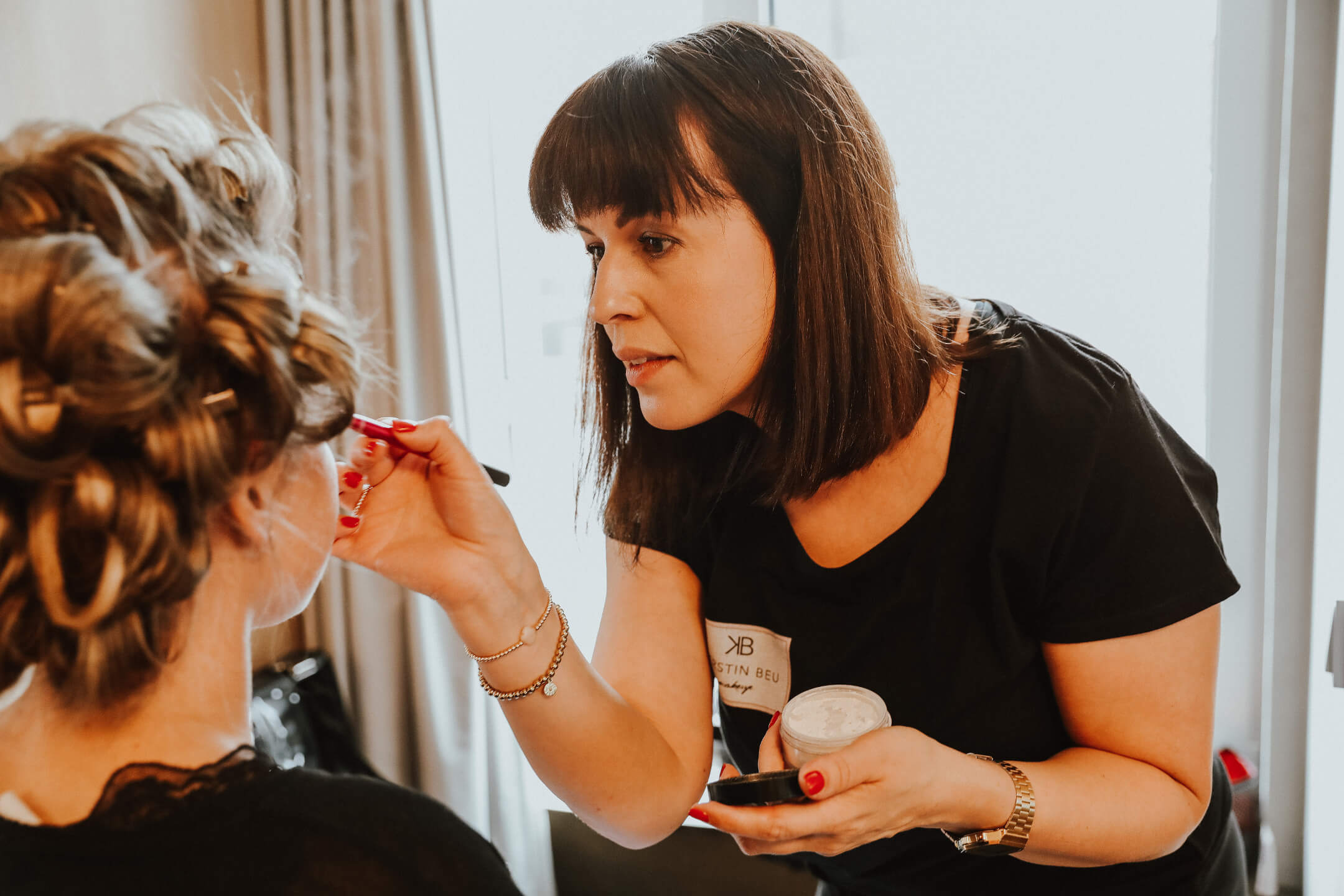 Beautician is making up the bride