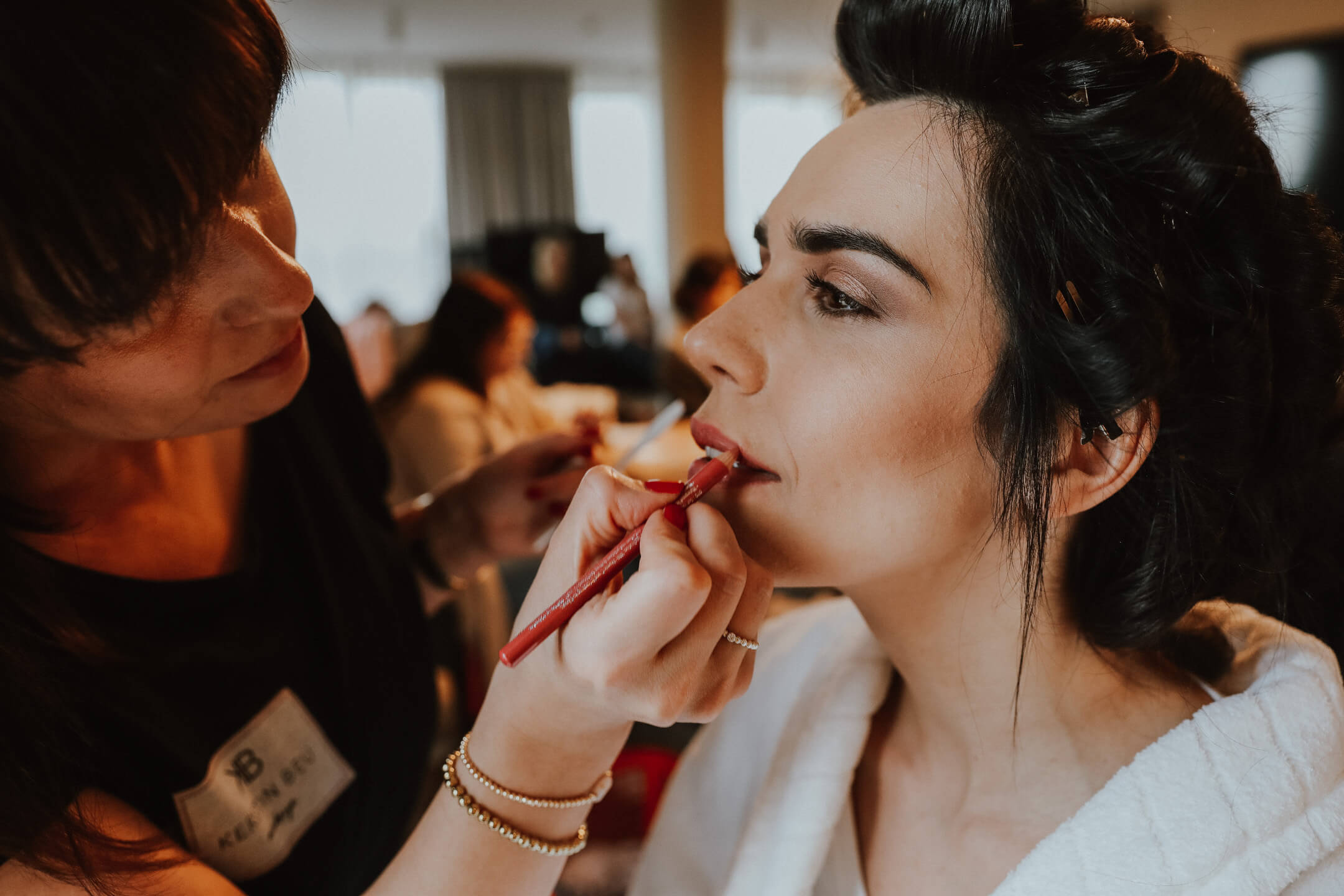 Beautician is making up the bride