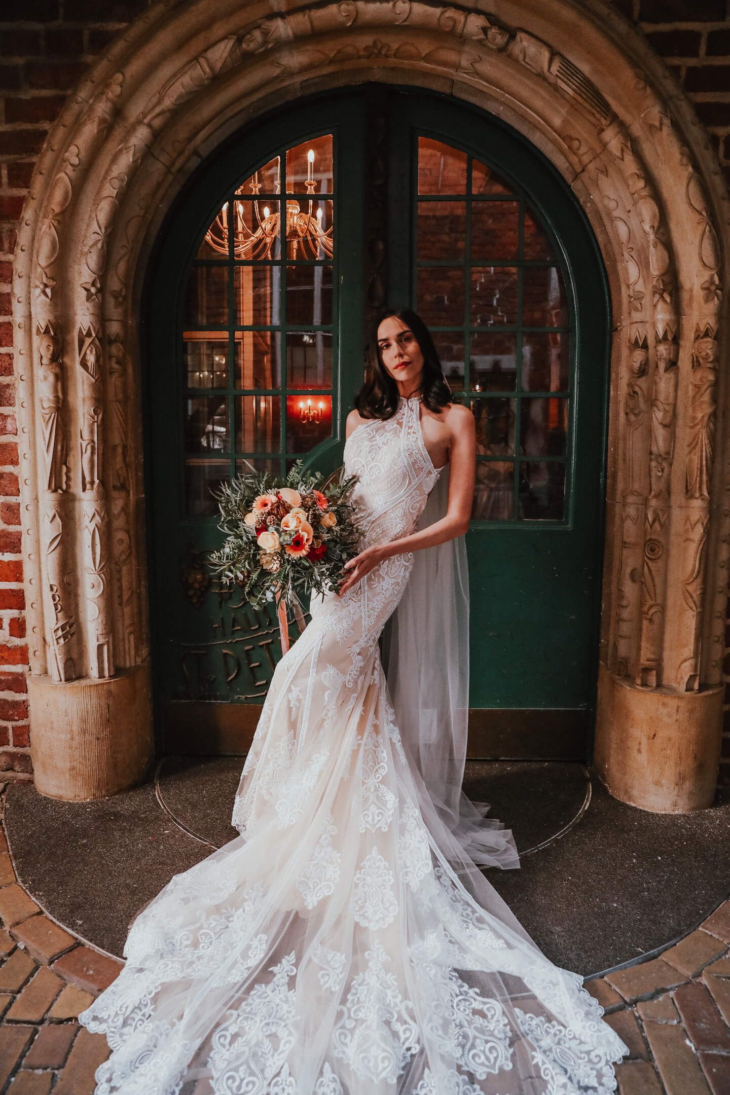 Porträtfoto einer Braut mit langem weißen Kleid und lachsfarbenen Blumenstraße