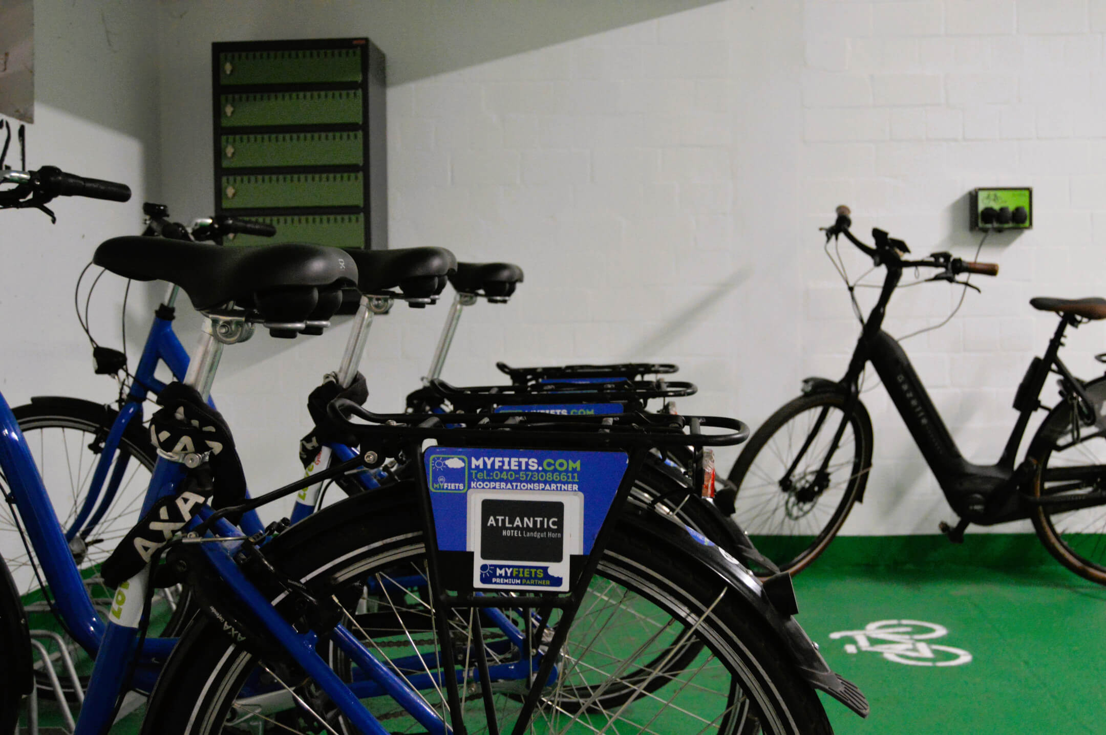 Fahrradverleih im ATLANTIC Hotel Landgut Horn Bremen mit blauen und schwarzen Fahrrädern in einem Abstellraum.