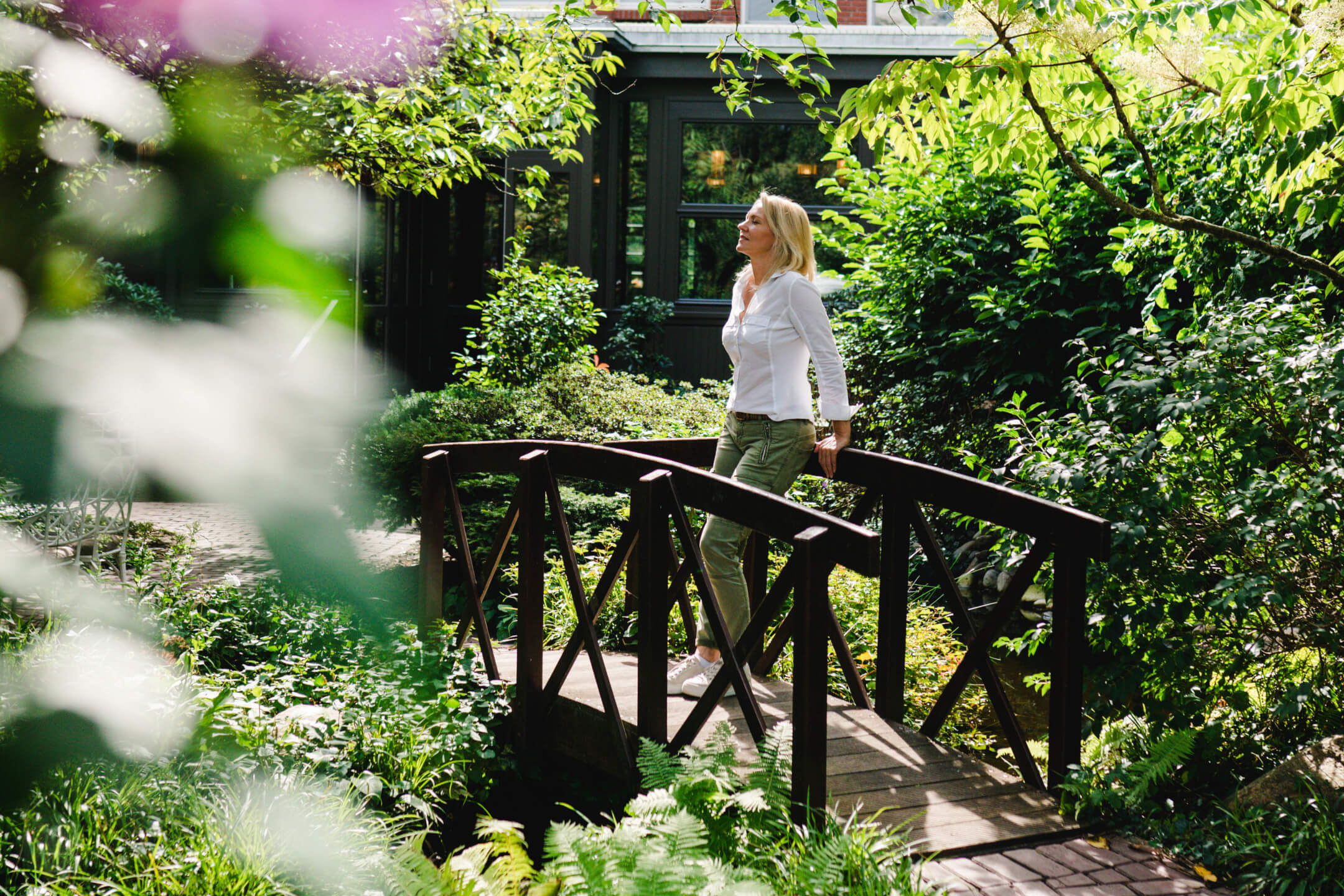 Eine Frau genießt das schöne Wetter im Garten vom ATLANTIC Hotel Landgut Horn