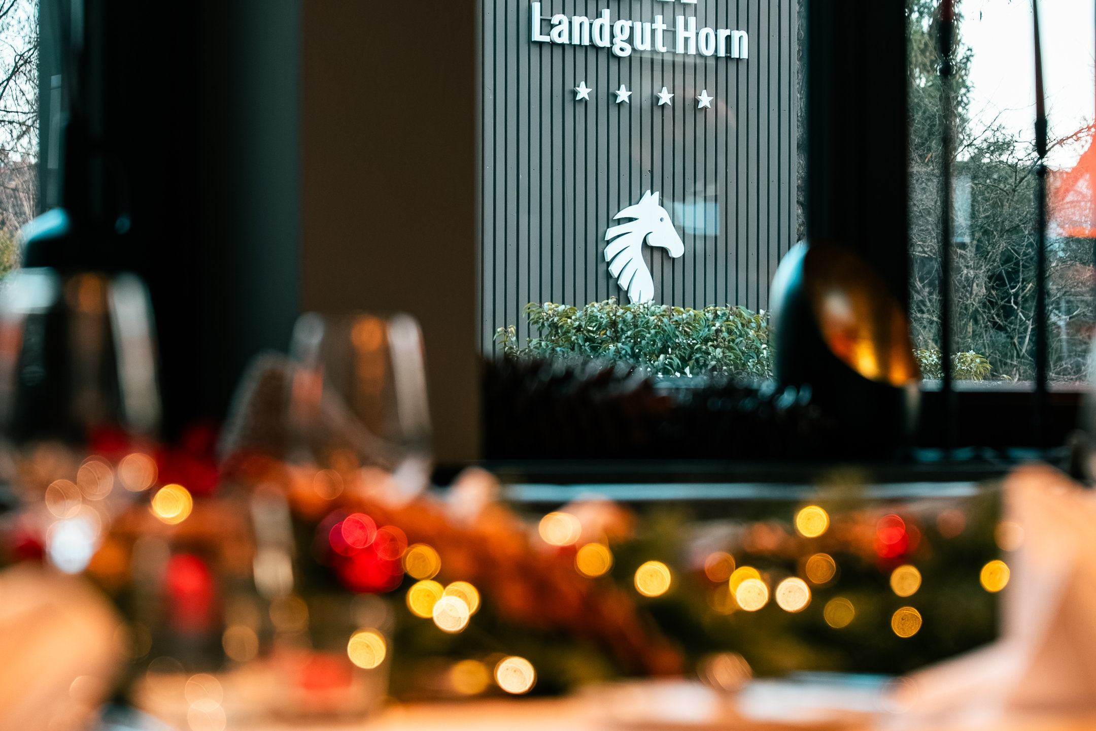 Blick auf das Schild vom Landgut Horn, innen ein weihnachtlich gedeckter Tisch mit Lichterkette.