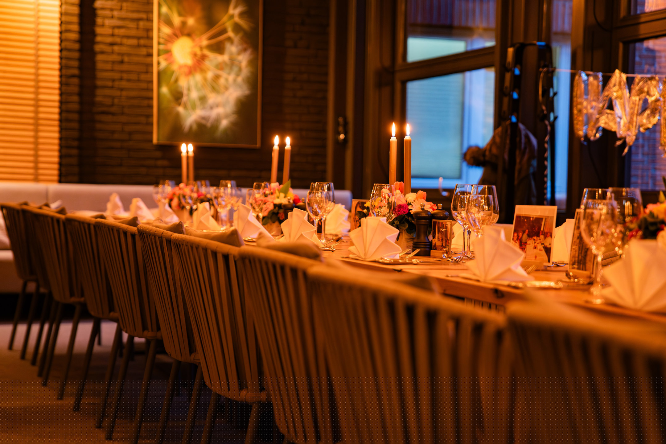 Festlich eingedeckte Tafel mit Blumen und Kerzen im Wintergarten.