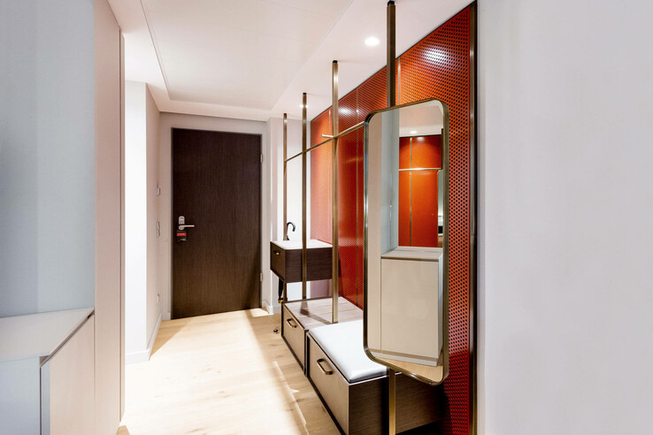 Modern hotel corridor with wooden floor, dark door, red wall paneling and mirror in the ATLANTIC Grand Hotel Bremen.
