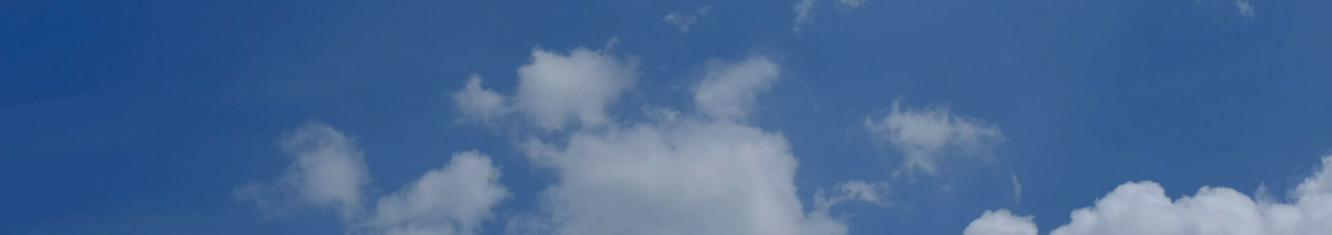 Blauer Himmel mit weißen, lockeren Wolken am Tag.
