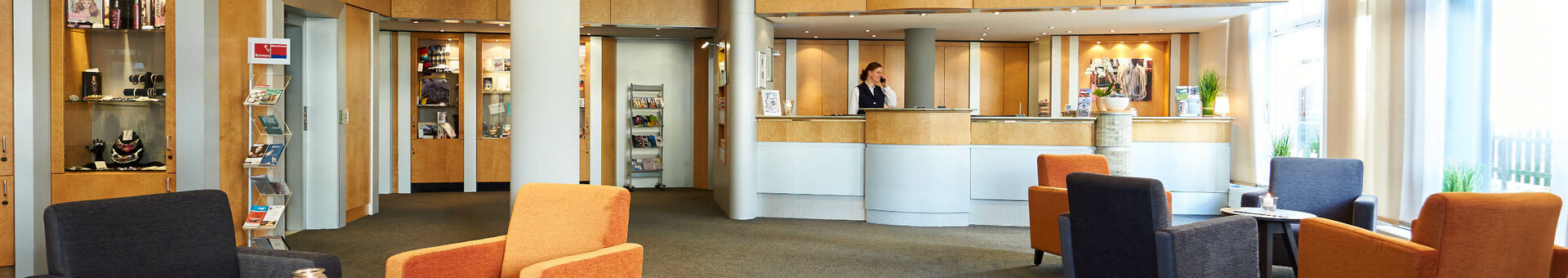 ATLANTIC Hotel Vegesack – Lobby Helle Lobby des ATLANTIC Hotel Vegesack mit Empfangstresen, Sitzbereich und moderner Beleuchtung.
