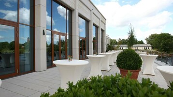 Terasse vor dem Festsaal Wilhelmshaven Terrasse des ATLANTIC Hotels Wilhelmshaven mit Stehtischen, Pflanzen und Blick auf den Himmel.