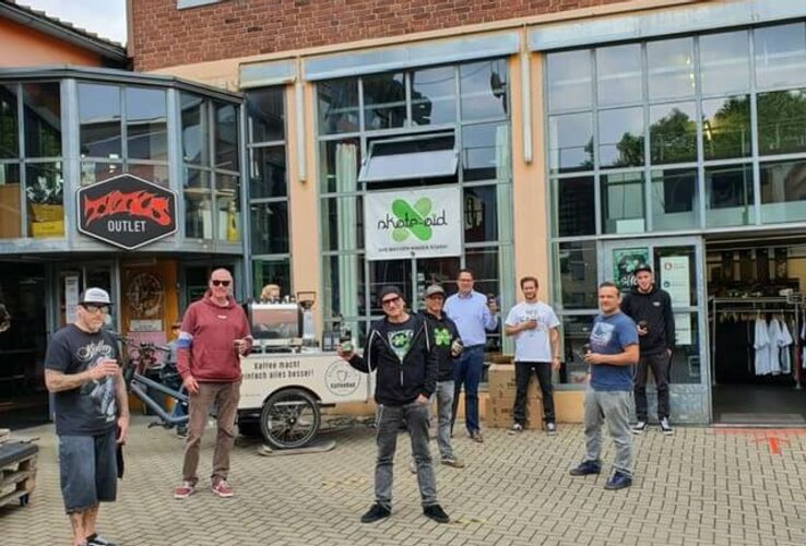 Group of people standing in front of a brick building with large windows, smiling and relaxed.