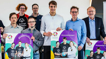 Gruppe von Menschen präsentiert Plakate für die Special Olympics Landesspiele Münster 2024 im ATLANTIC Hotel.