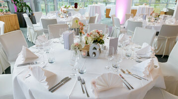 Elegante, festlich gedeckte Tische im ATLANTIC Hotel Universum mit Blumenarrangements und weißer Tischwäsche.
